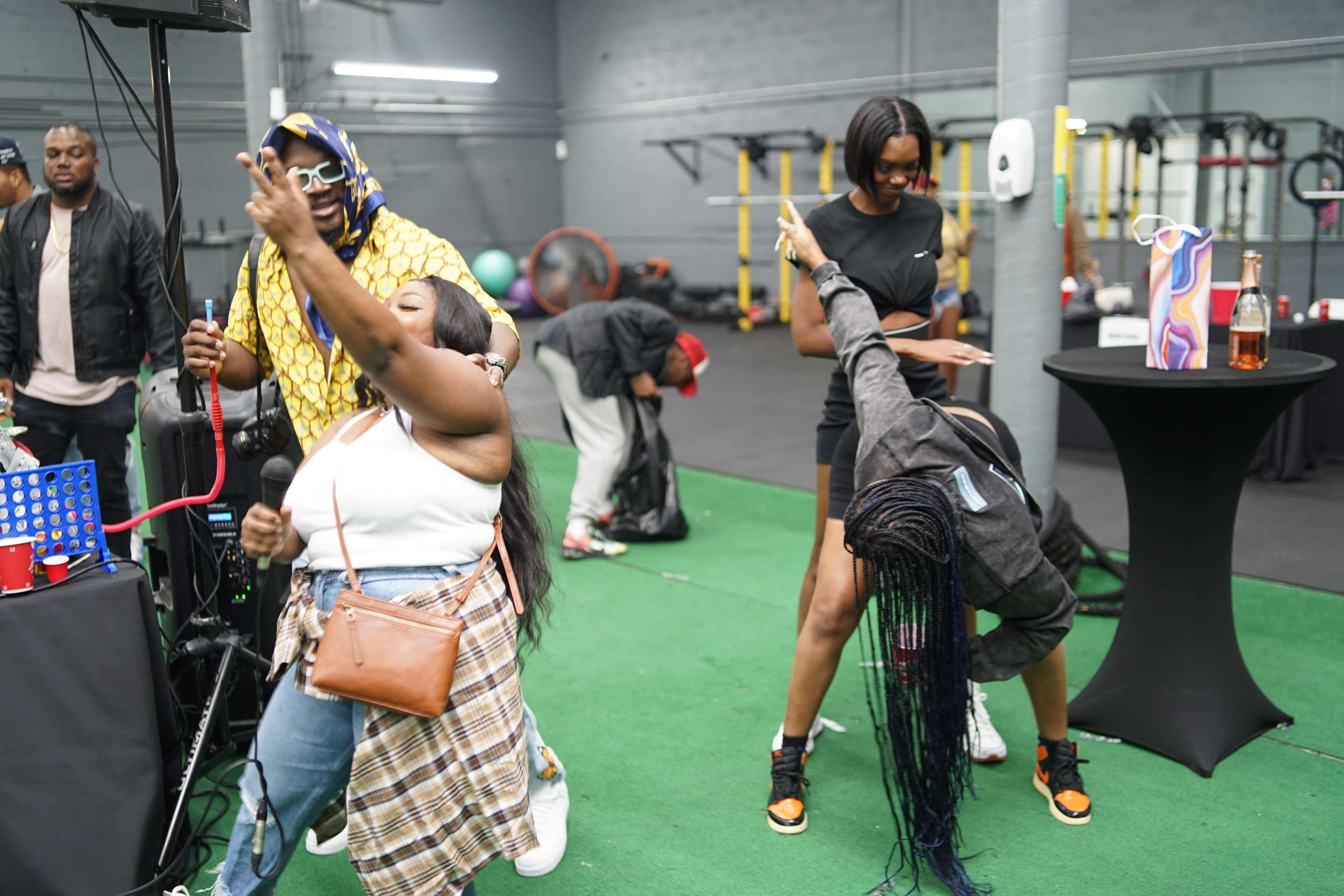 A group of people are dancing and socializing in a gym-like space equipped with exercise equipment.