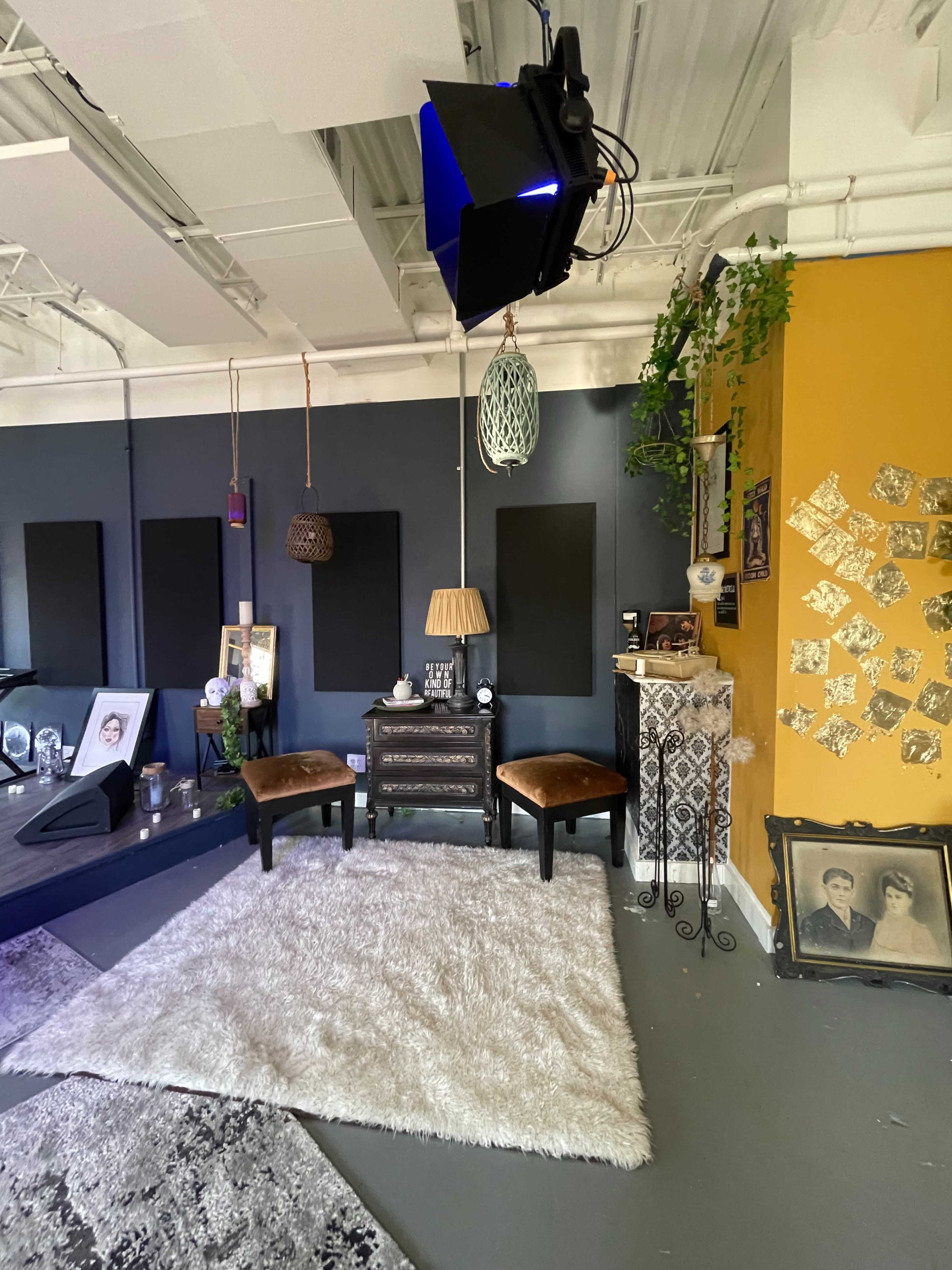 A room setup with two chairs facing a small table, decorative items on the walls, and light fixtures hanging from the ceiling.