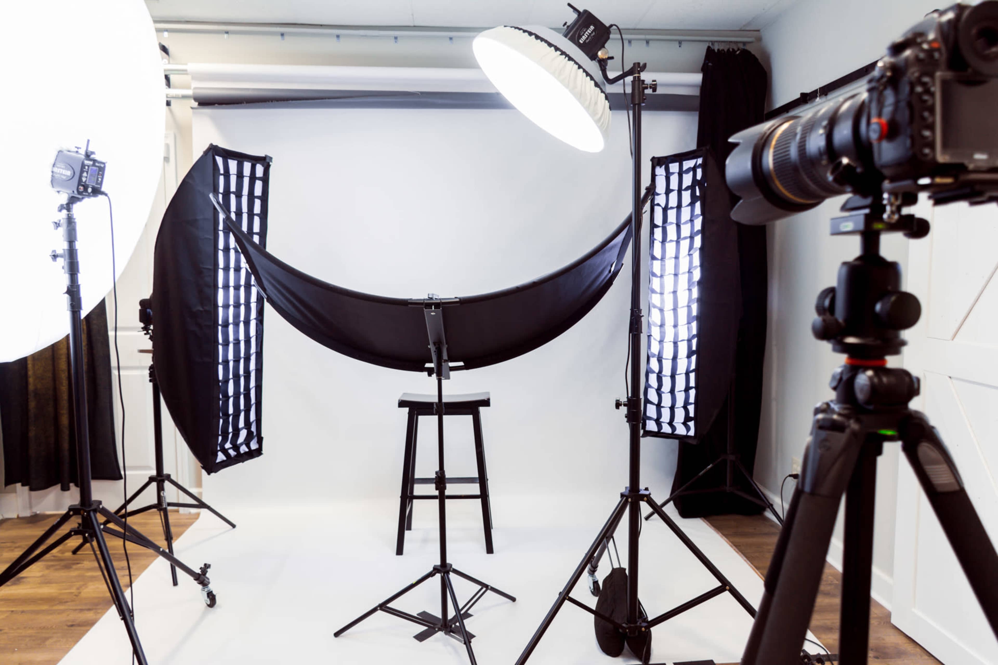 A photography studio setup with a chair in the center, surrounded by softbox lights and a backdrop.