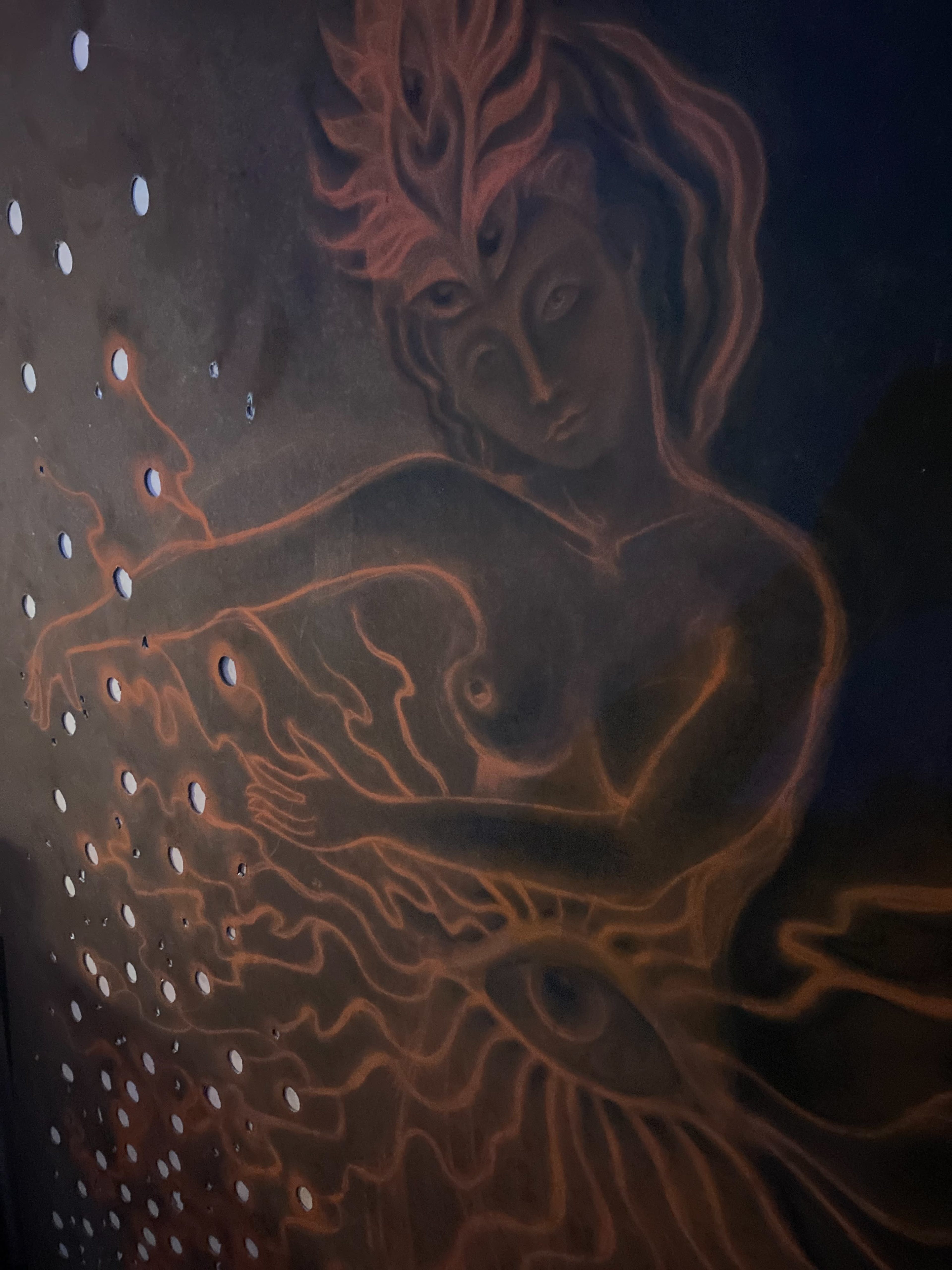 The image features a large mural of a figure with flowing hair and outstretched arms, surrounded by glowing patterns on a dark background.