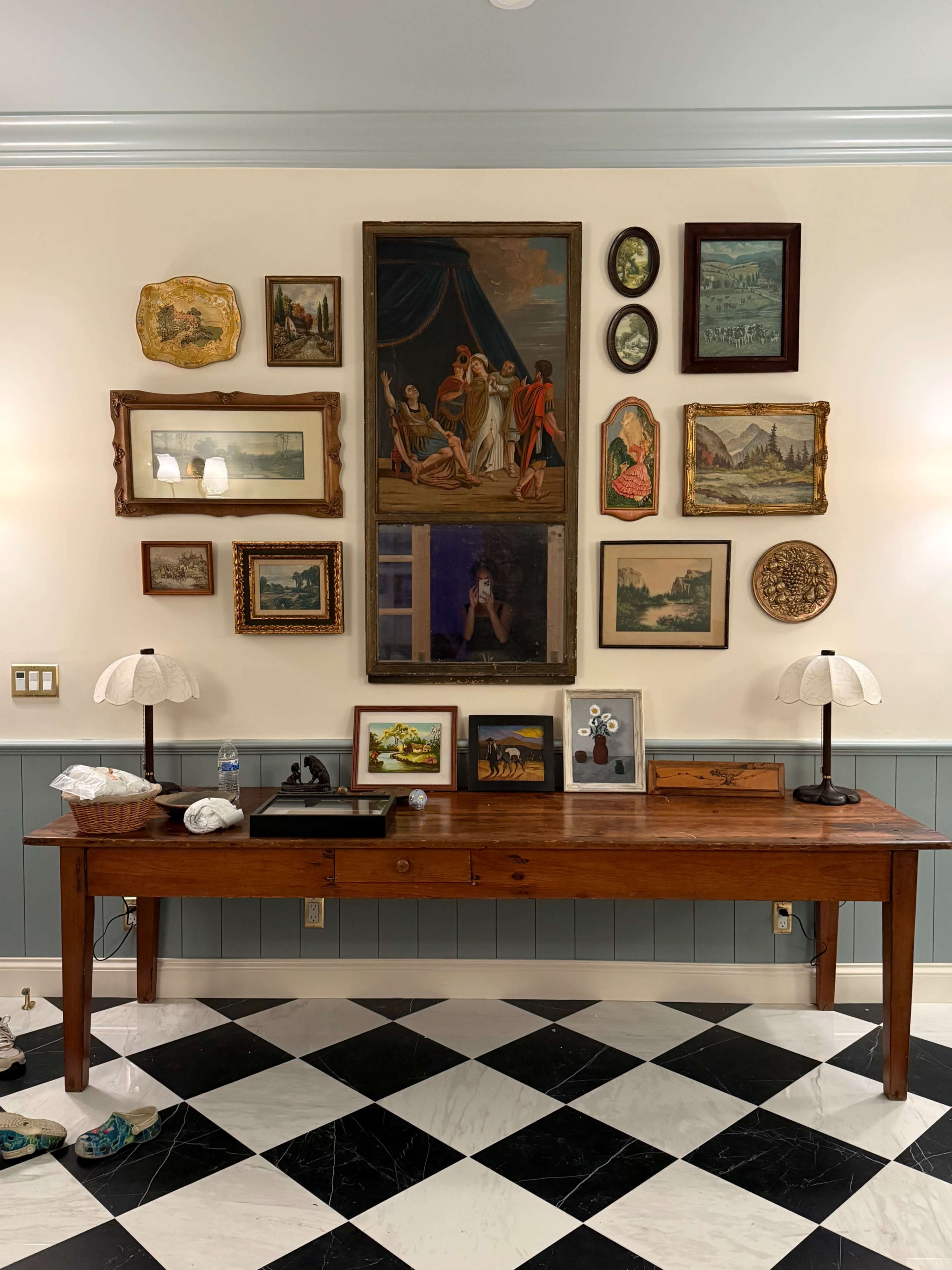 A wooden table is positioned against a wall adorned with various framed artworks and decorative objects.