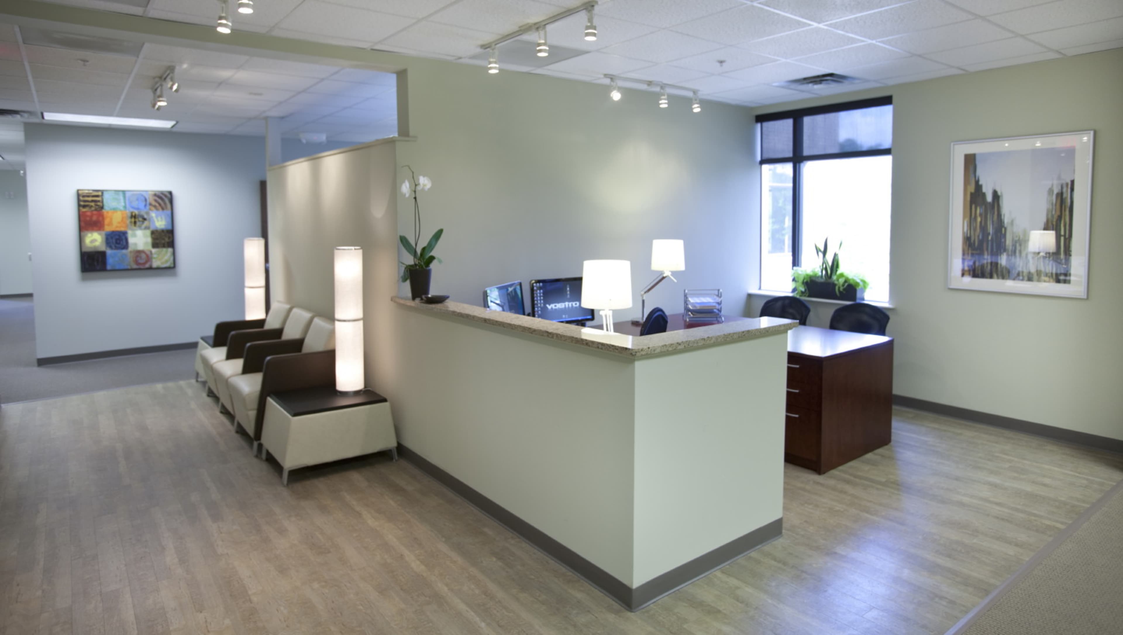 A modern office reception area with a front desk, seating arrangements, and artwork on the walls.