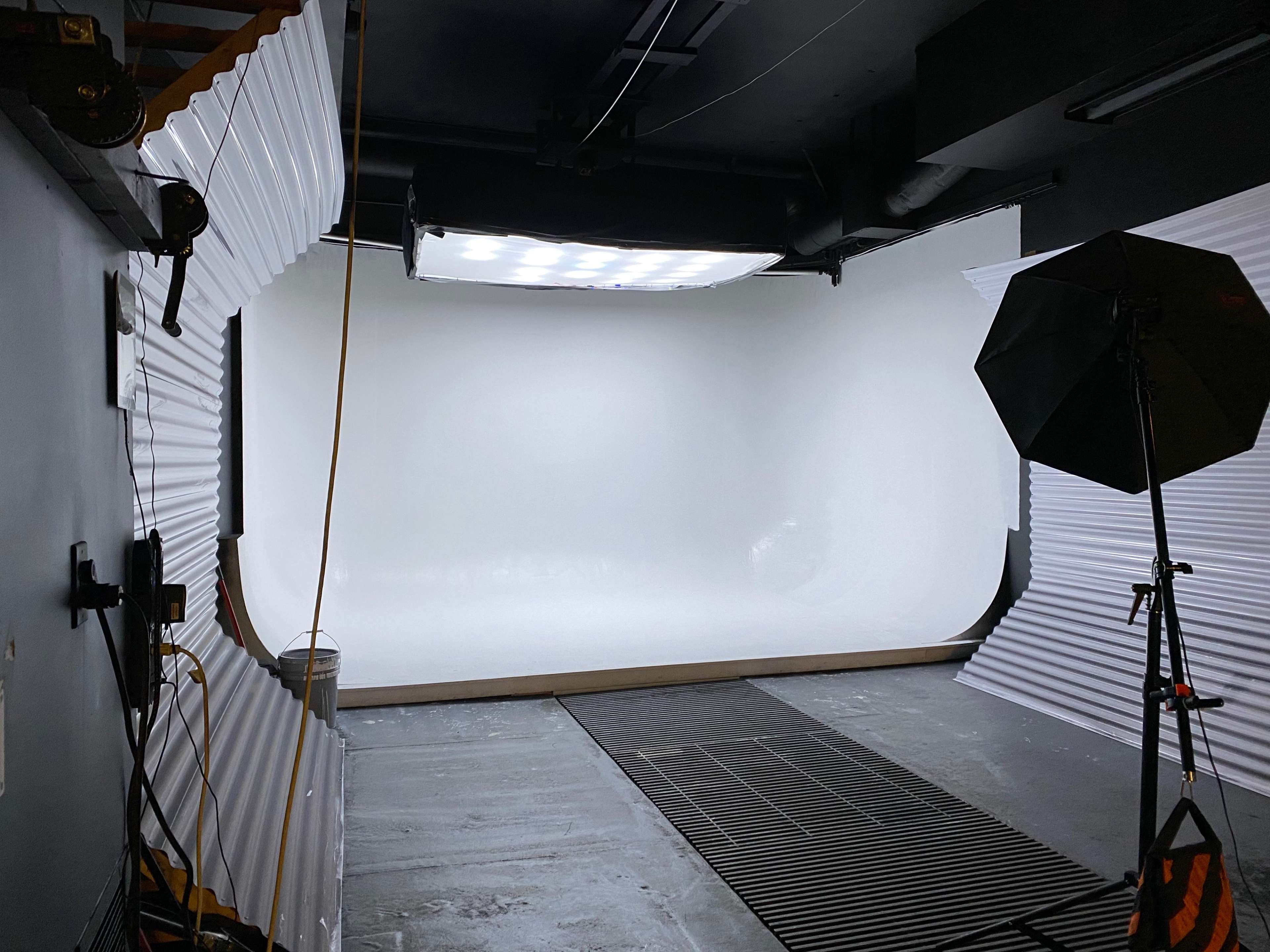 A photography studio with a seamless white backdrop and lighting equipment set up.
