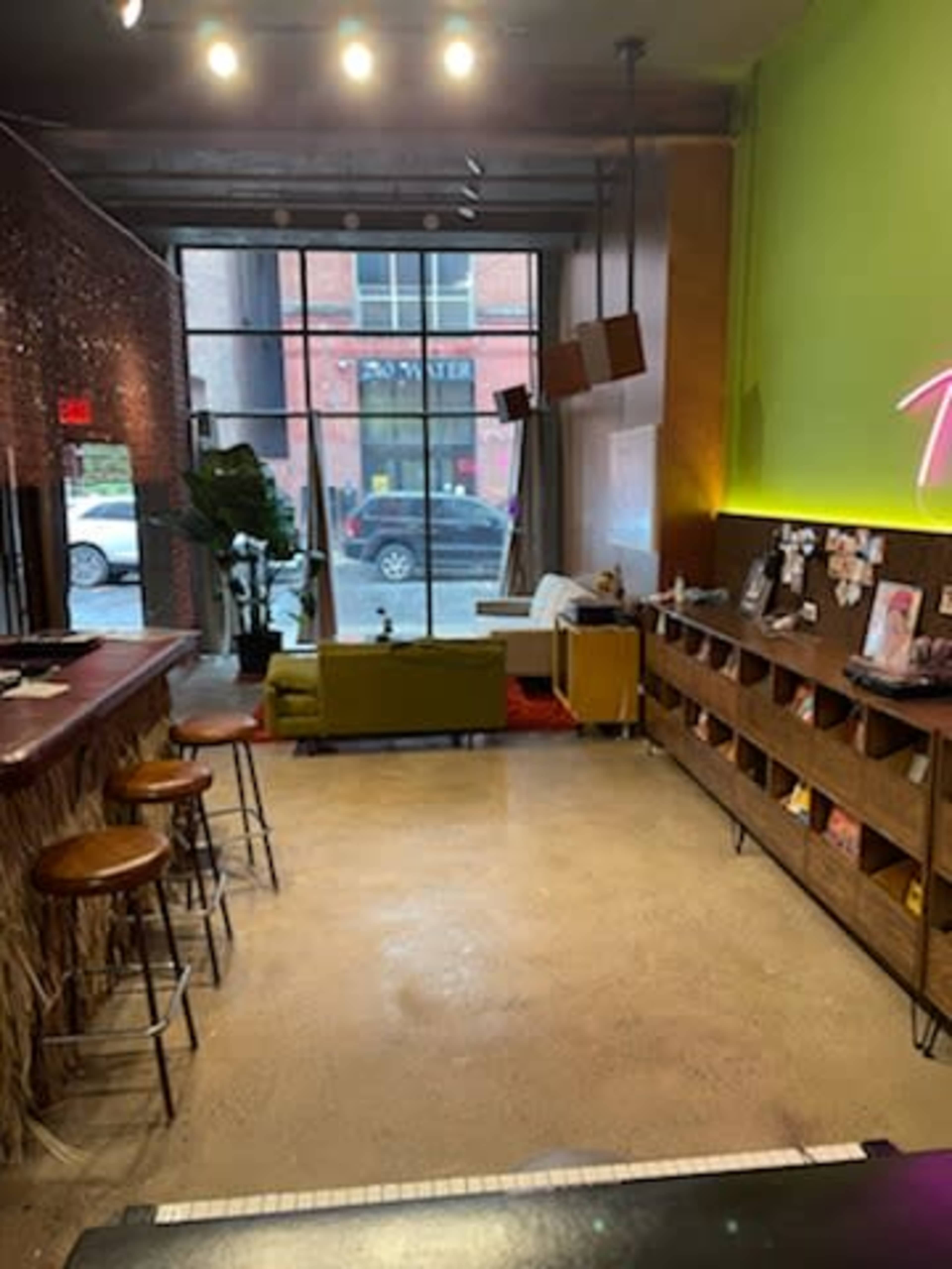 A modern café interior featuring a bar area, seating arrangements, and a large window with a view of the street outside.