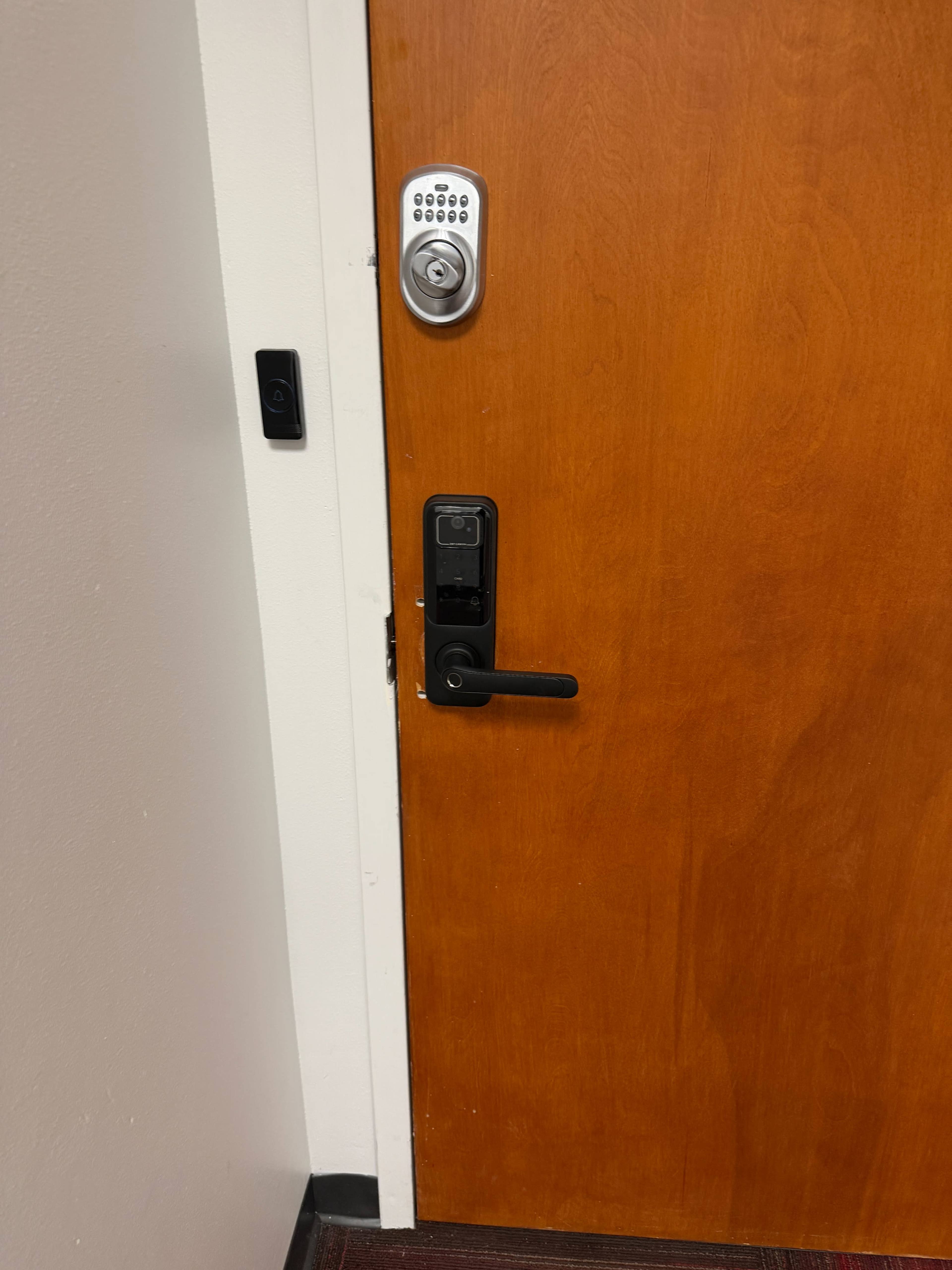 The image shows a wooden door with both a keypad and a digital lock installed on it.