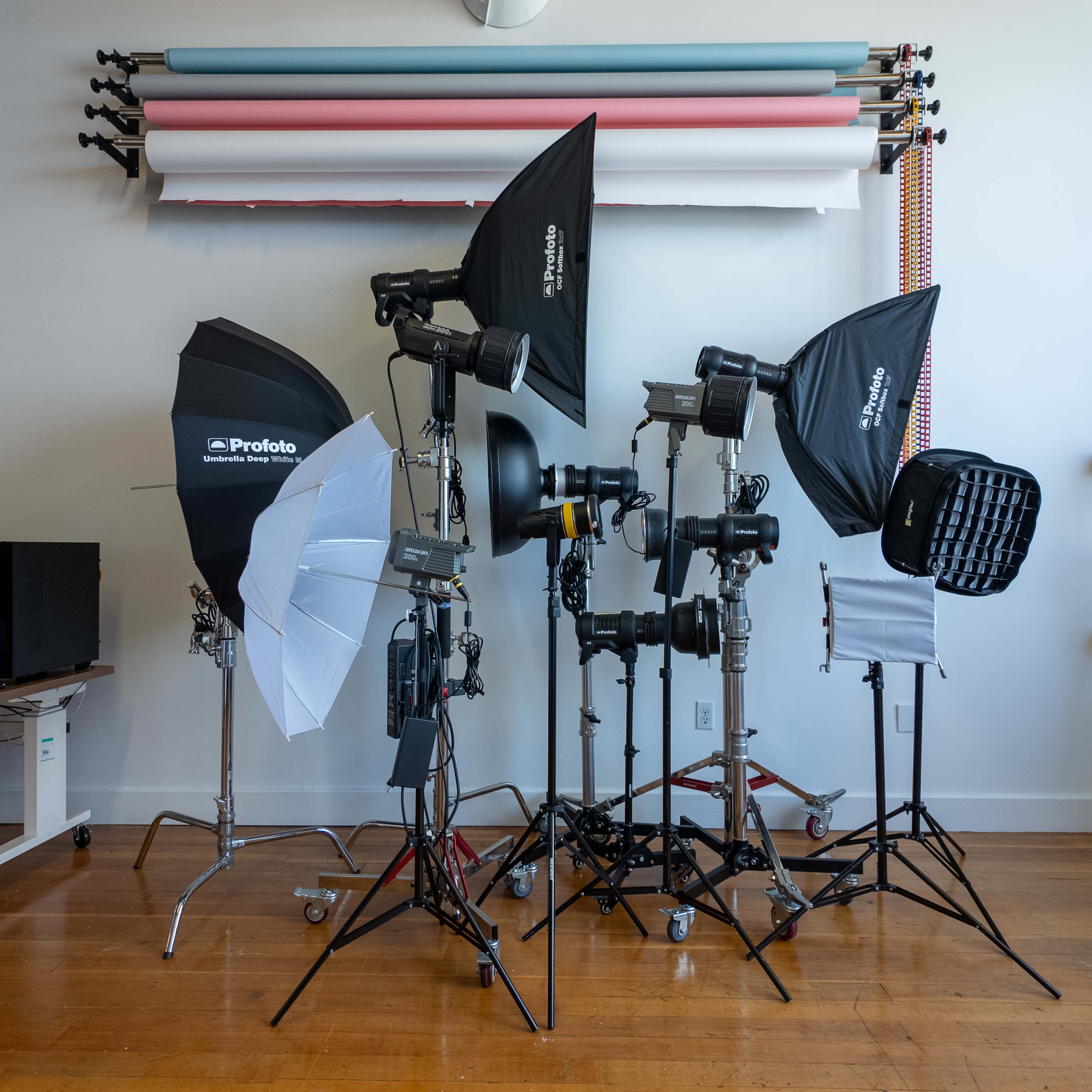 A collection of photography studio lighting equipment is set up in a well-lit room.