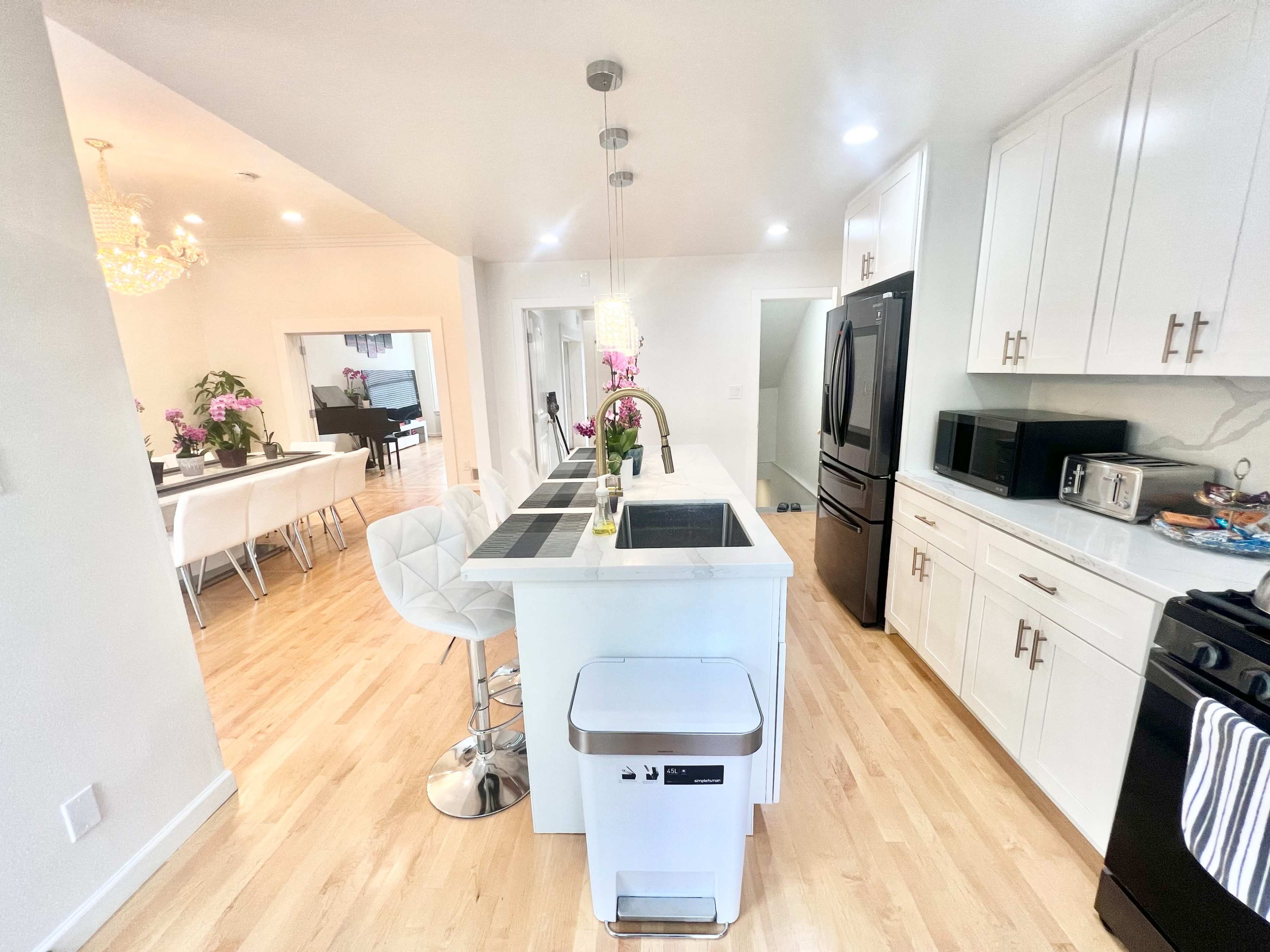 The kitchen features modern white cabinetry, a central island with bar seating, and stainless steel appliances.