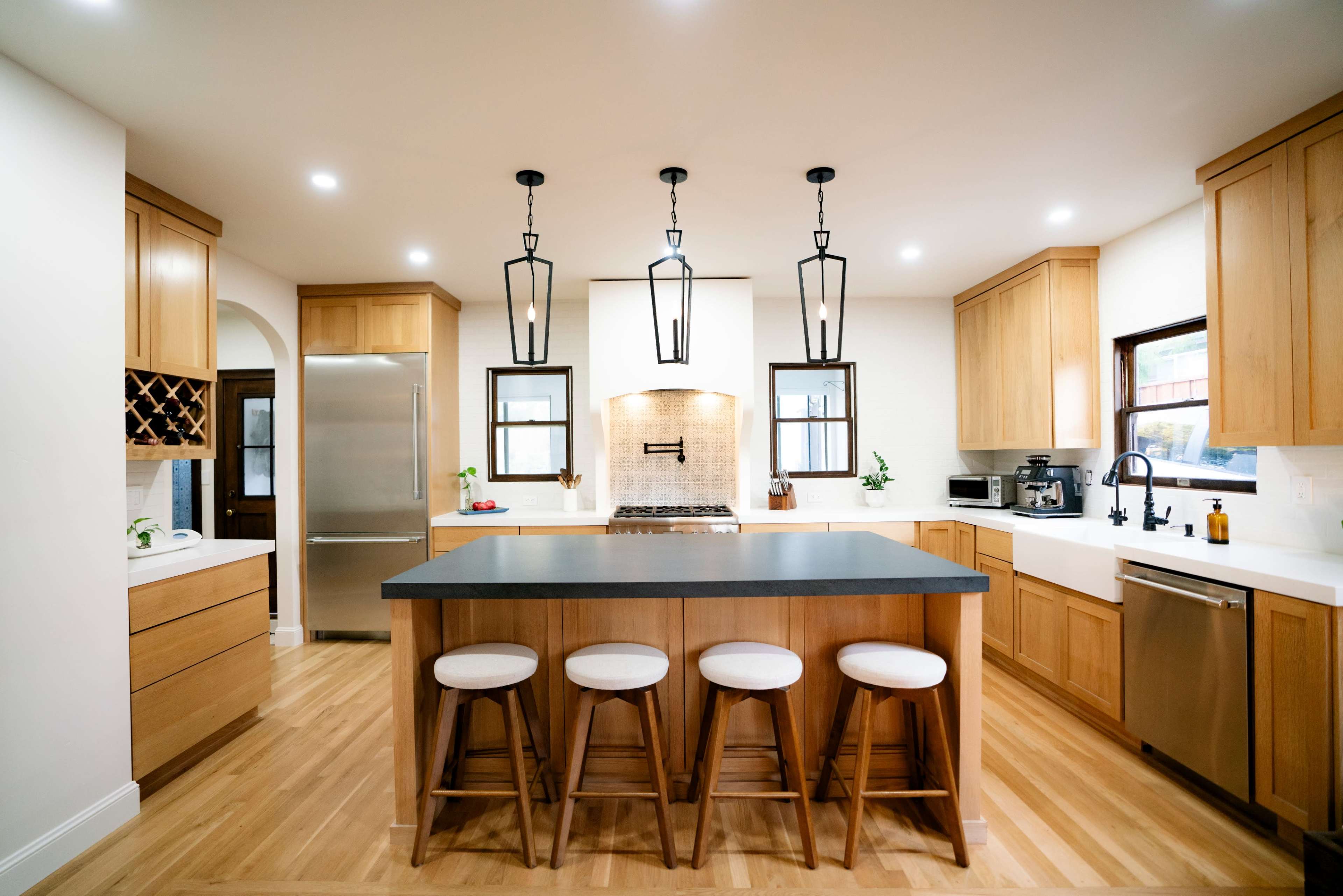 The kitchen features wooden cabinetry, a central island with four stools, and modern appliances.