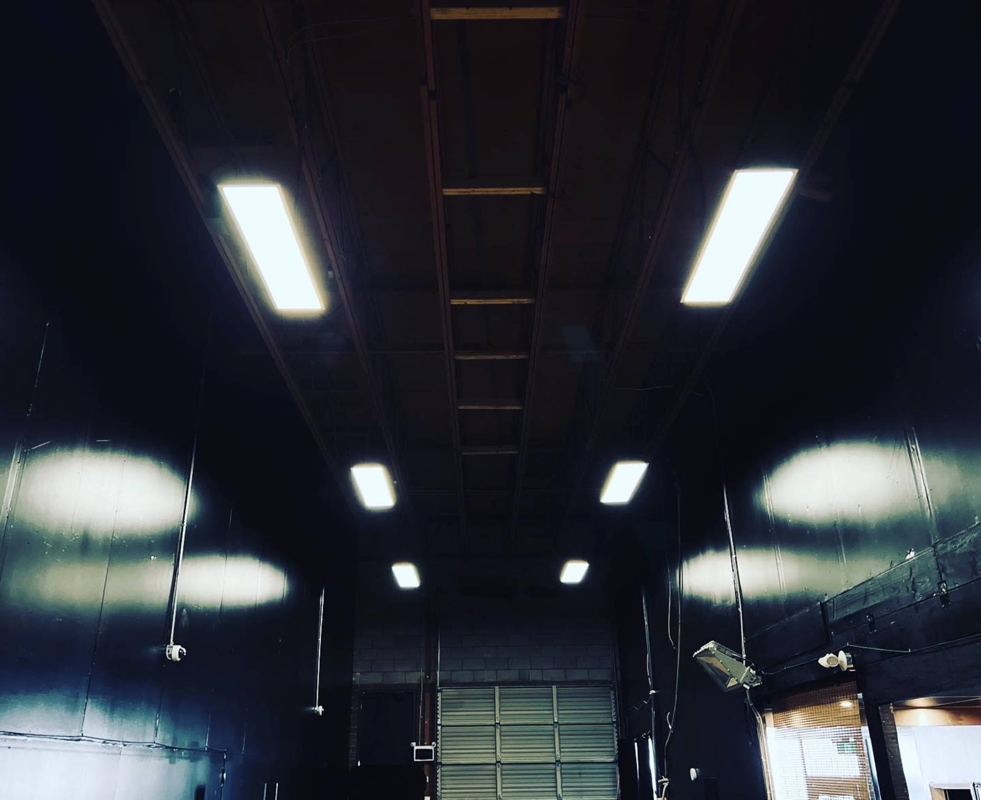 An industrial space with a high ceiling, illuminated by fluorescent lights, and dark walls.