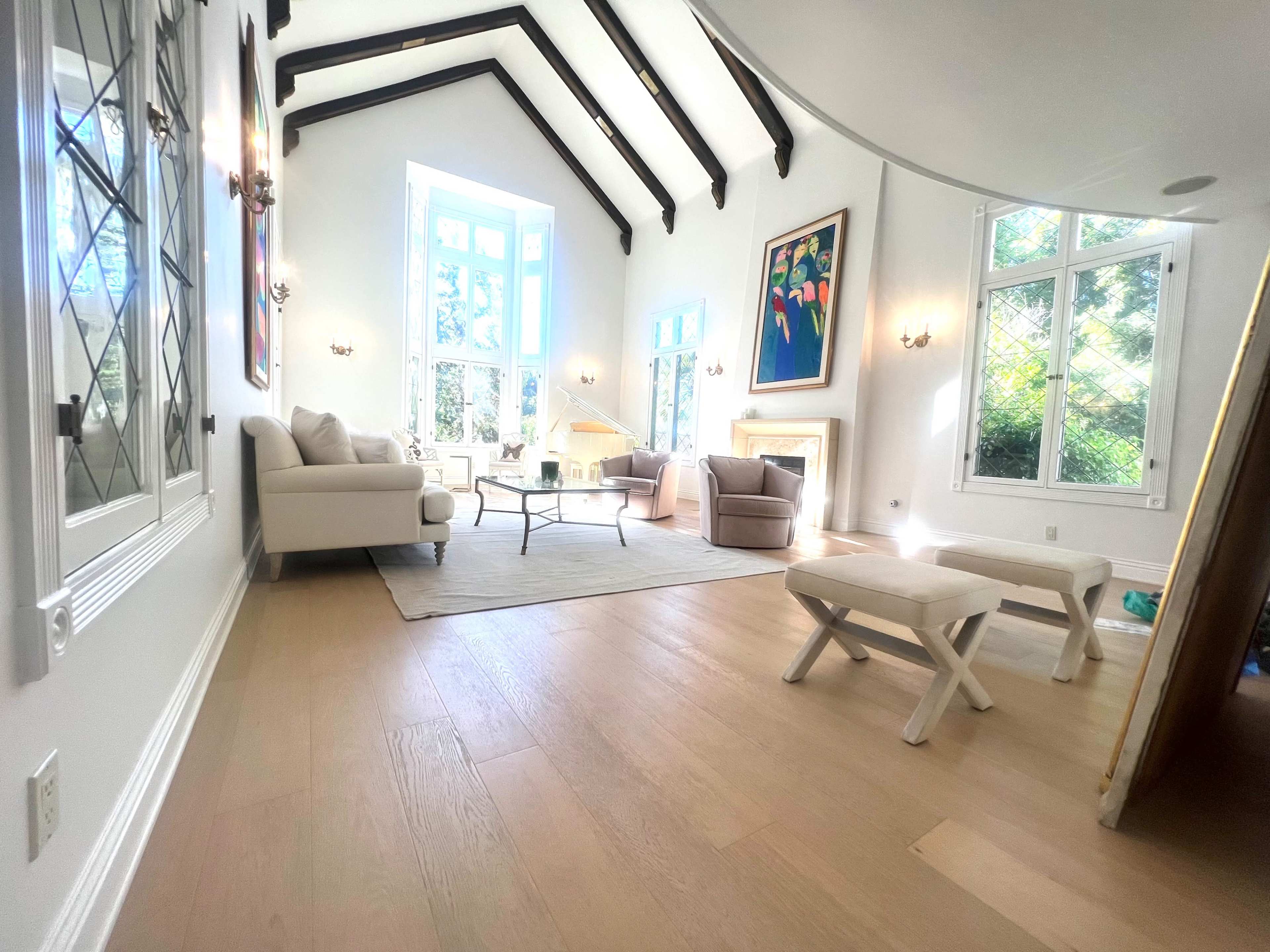 A spacious living room with high ceilings, large windows, and a light-colored sofa facing a coffee table.