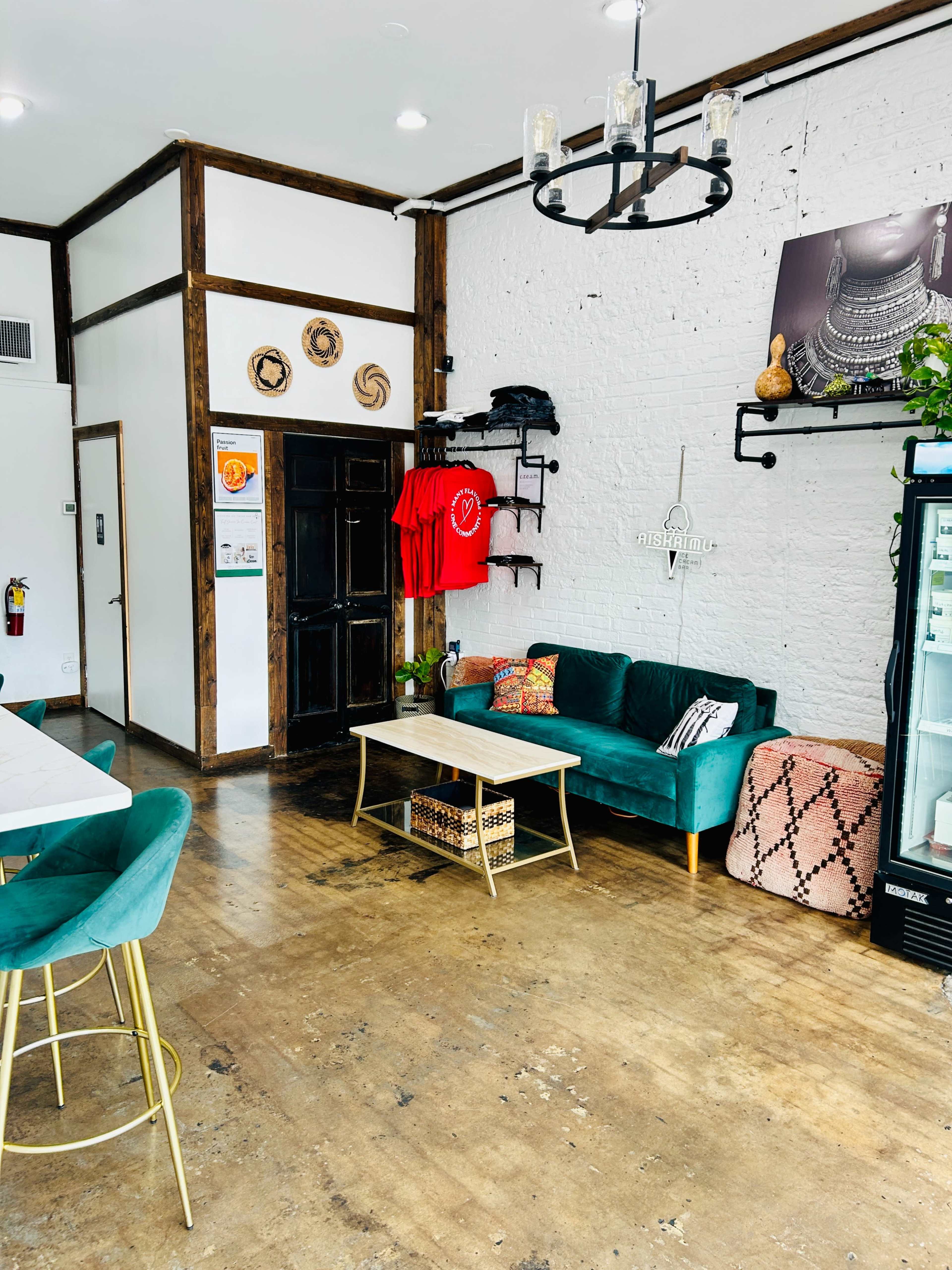 The image shows a cozy café interior featuring a green couch, a wooden table, and a wall with decorative elements.