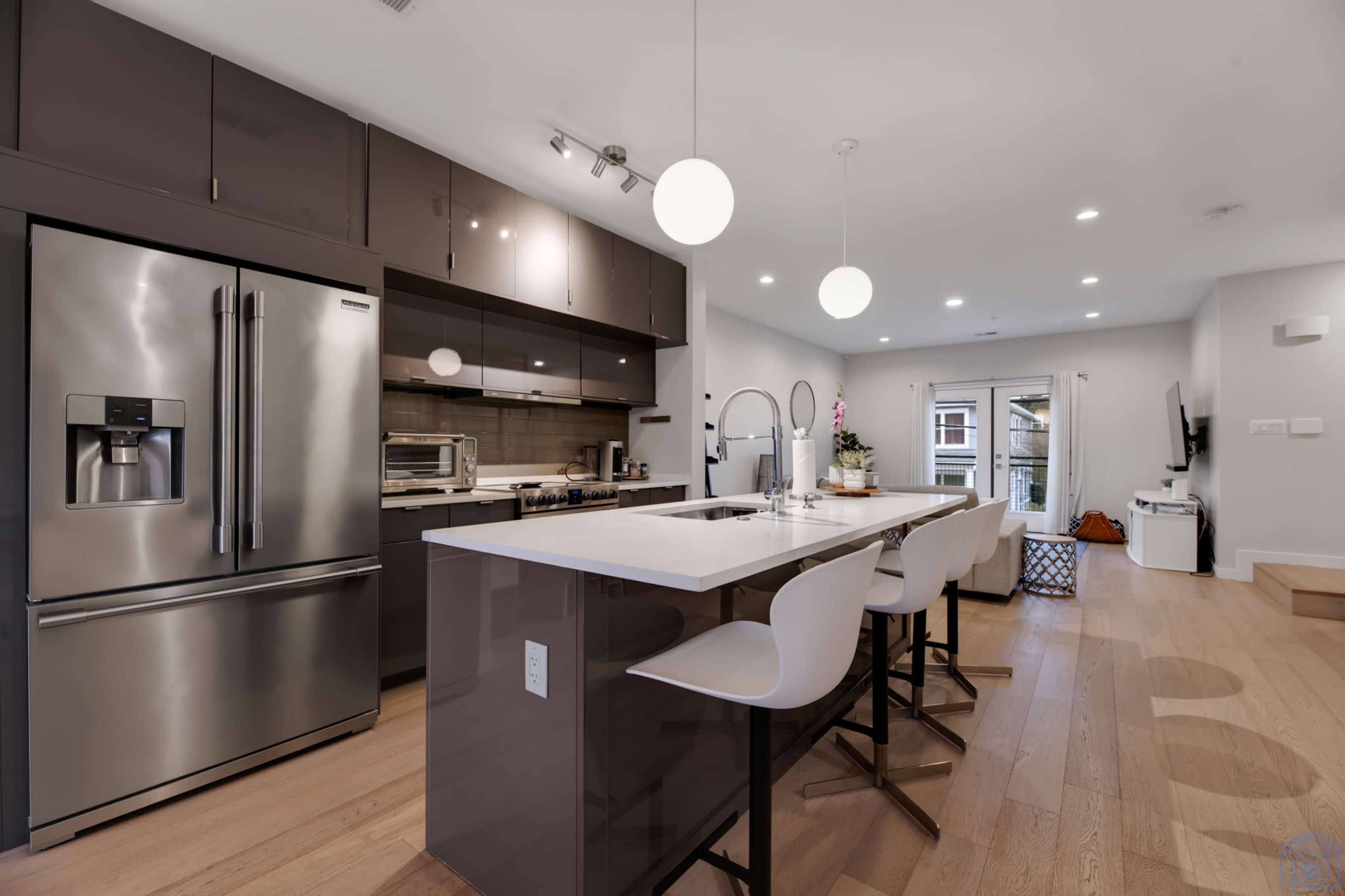 A modern kitchen with stainless steel appliances, a large island with seating, and a view of a patio through glass doors.