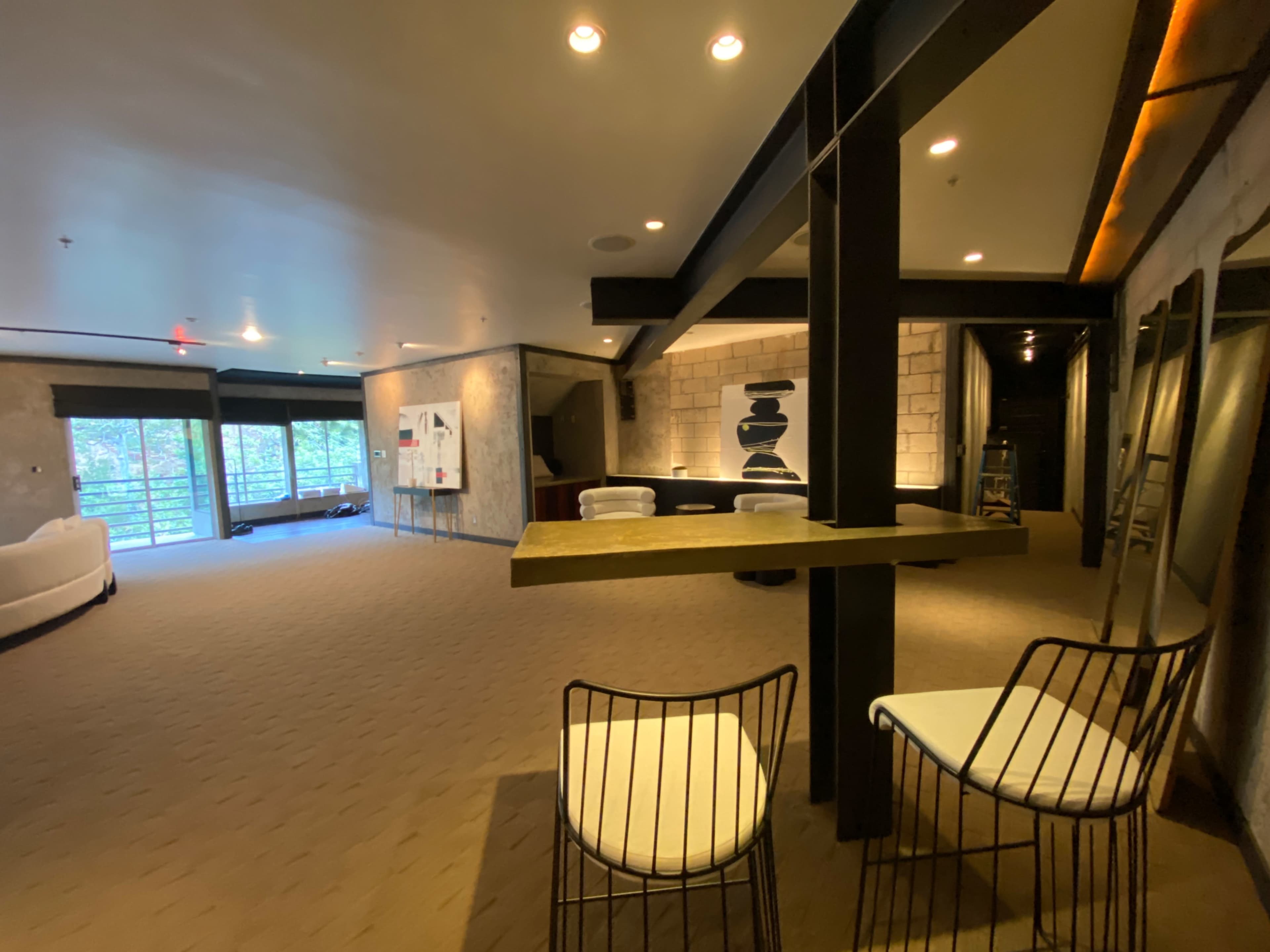 A spacious interior lounge area with a seating arrangement, large windows, and modern decor.
