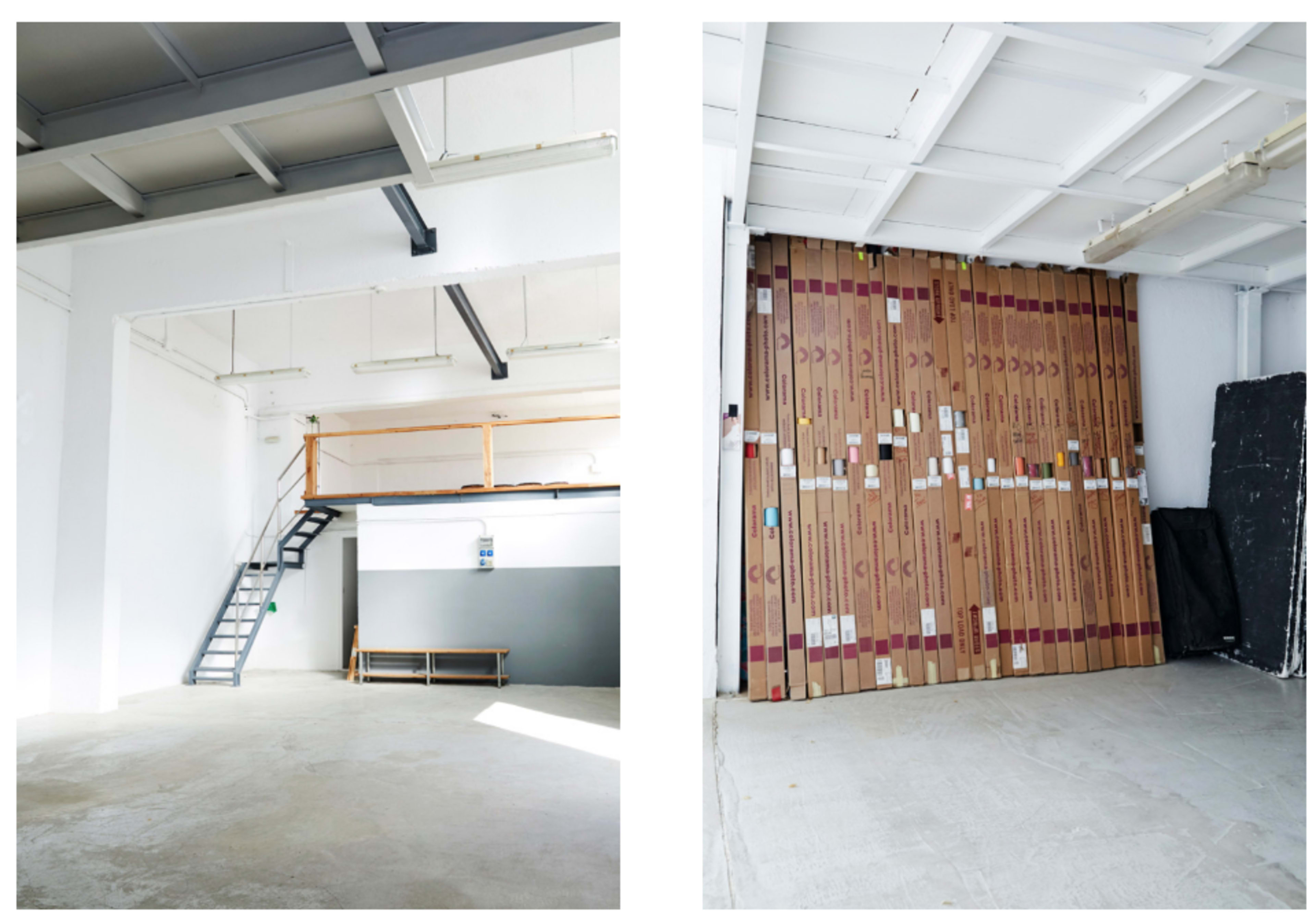A spacious room with a staircase on the left and a wall stacked with cardboard boxes on the right.