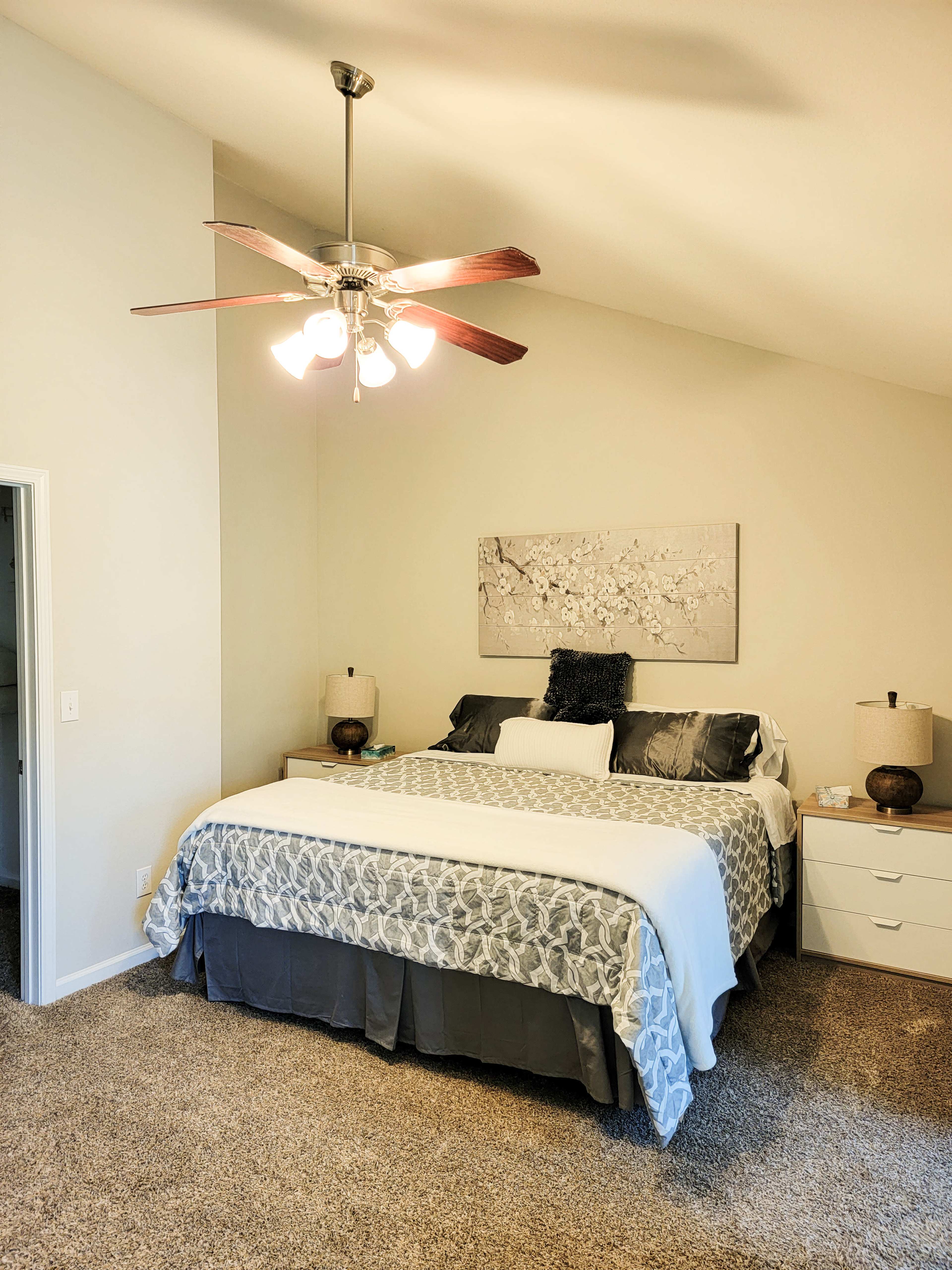 A well-furnished bedroom with a large bed, a ceiling fan, and two bedside tables.