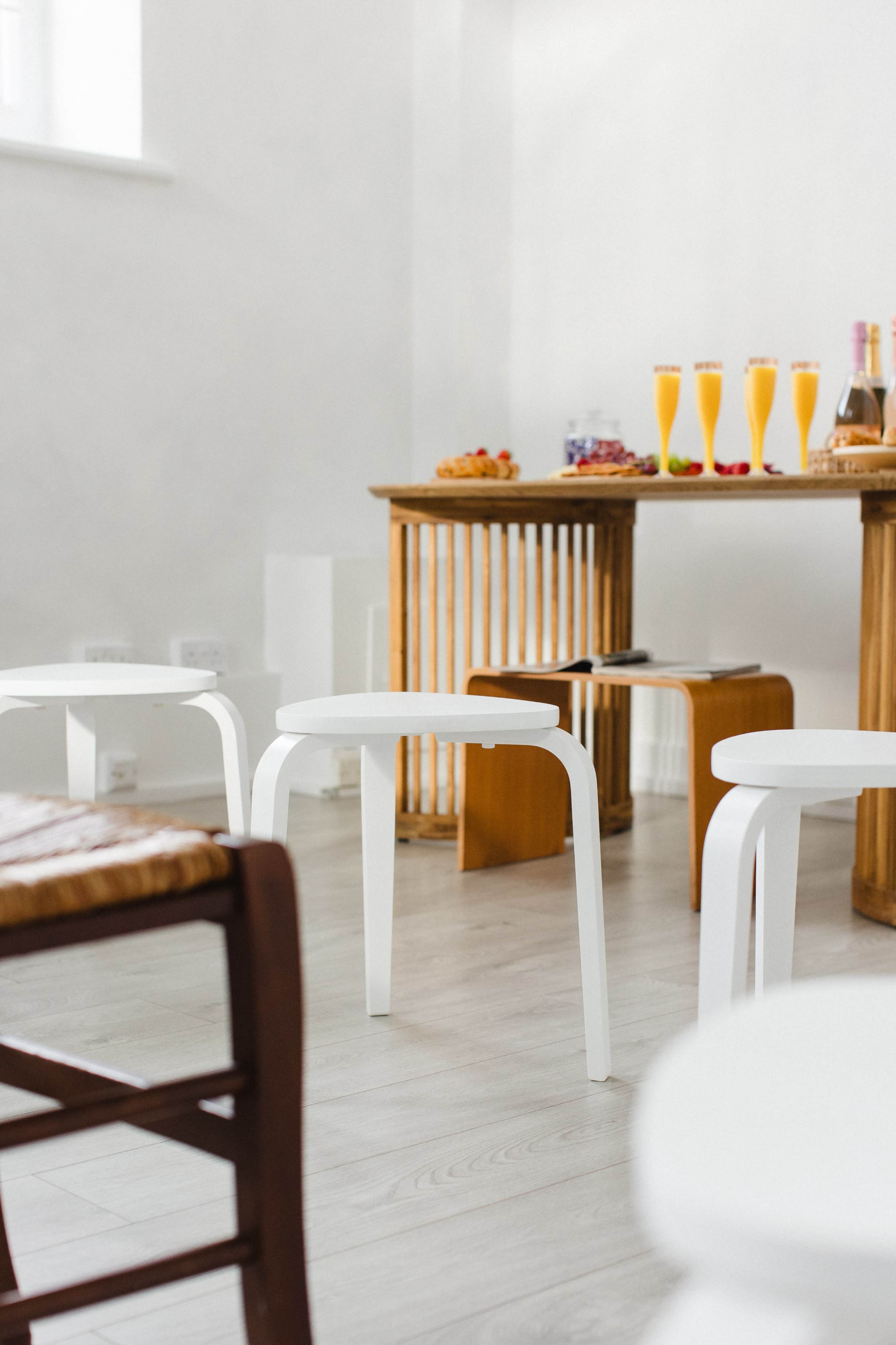 A table with drinks and snacks is set against a backdrop of white walls and minimalist seating.