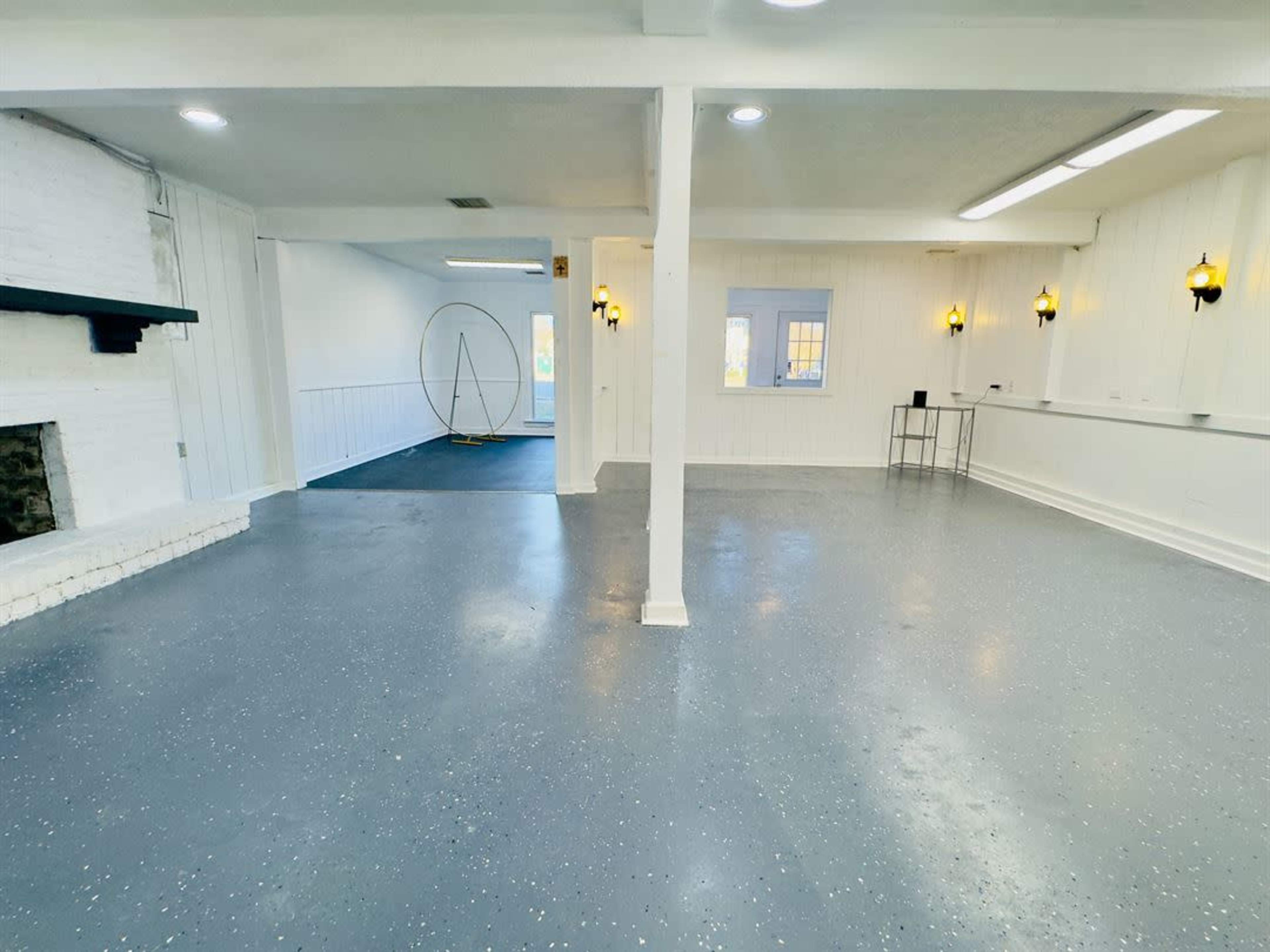 The image shows a spacious, empty room with white walls, a light gray floor, and a large circular structure in the corner.
