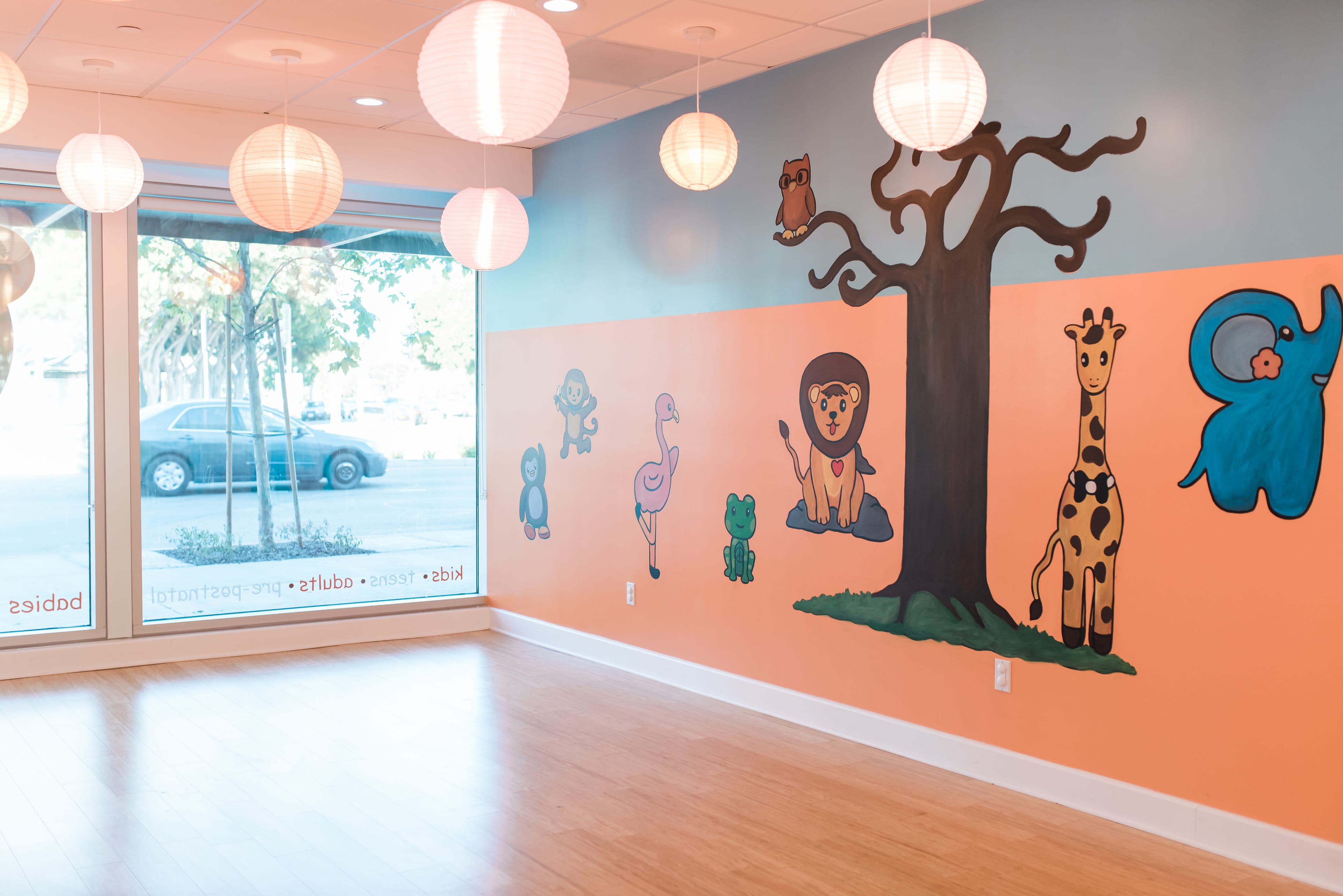 A brightly colored room featuring a mural with various animal characters on the walls and hanging light fixtures.