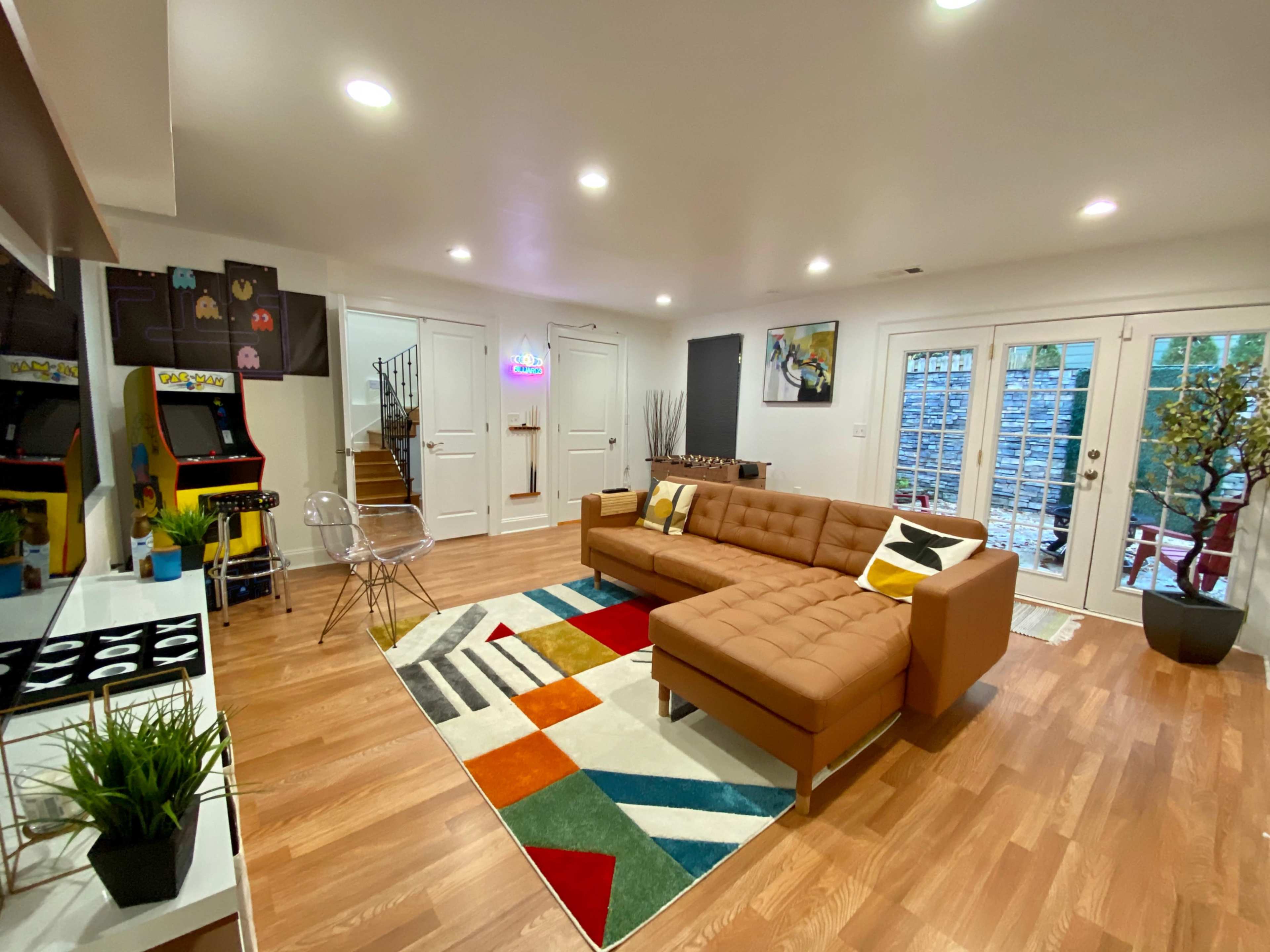A modern living room featuring a brown sectional sofa, colorful area rug, and access to a patio through glass doors.