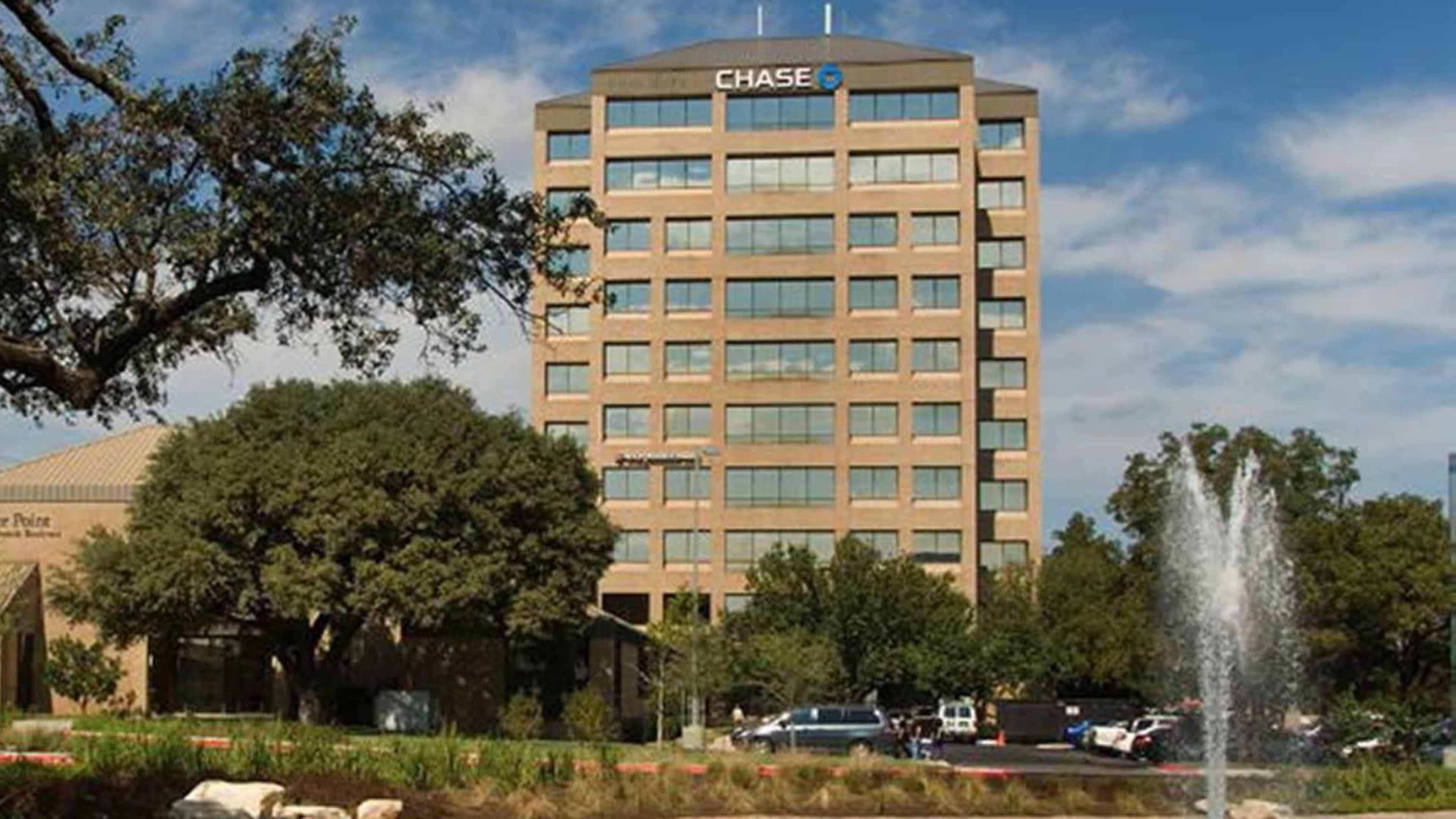 A multi-story Chase Bank building surrounded by trees and a fountain in the foreground.