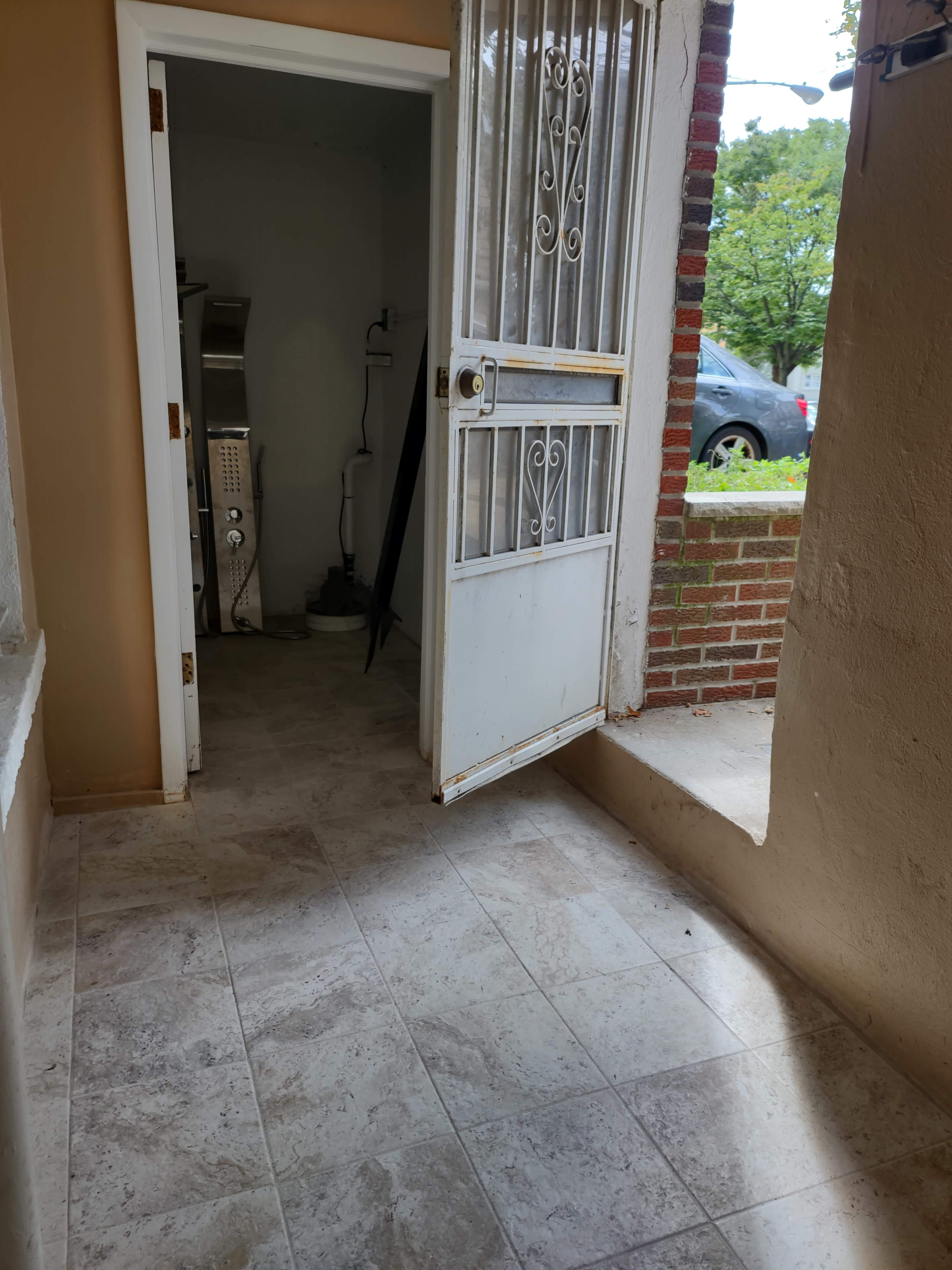 An open doorway leading into a room with tiled flooring and a visible kitchen area in the background.