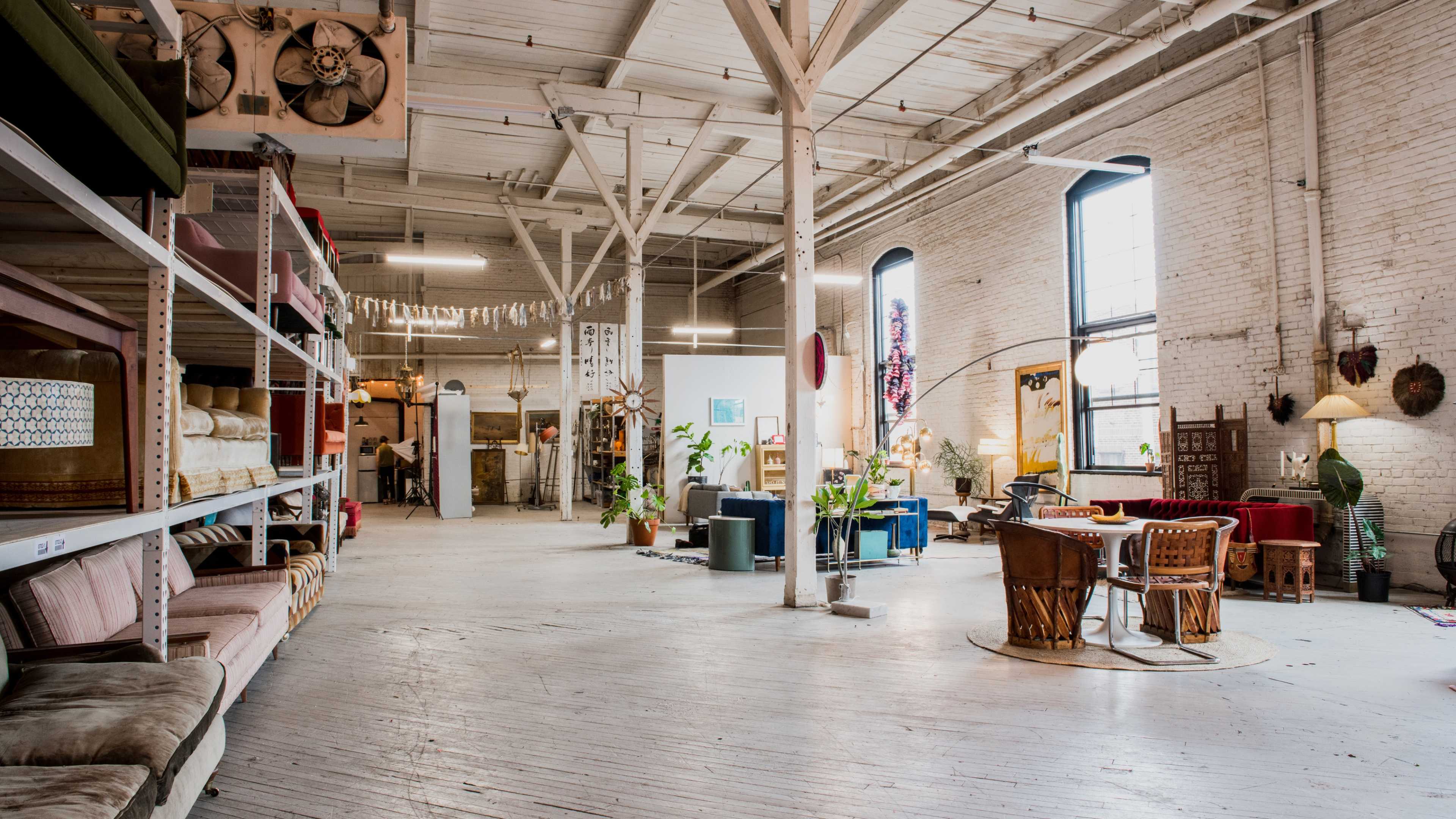 A spacious interior of a furniture store with white brick walls, various seating arrangements, and shelves displaying colorful textiles.