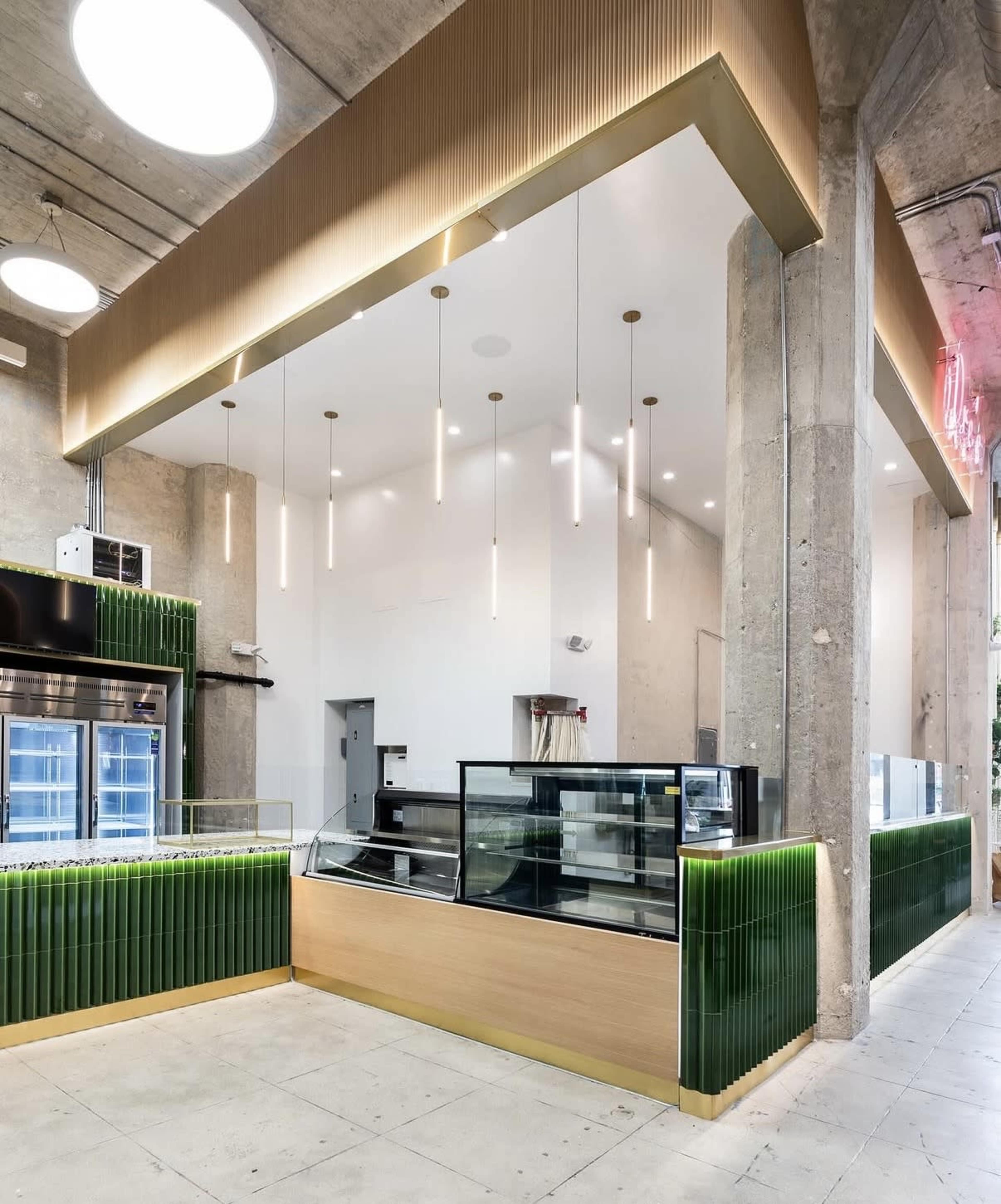 The image depicts a modern retail space featuring a glass display counter, minimalist design elements, and decorative lighting hanging from the ceiling.