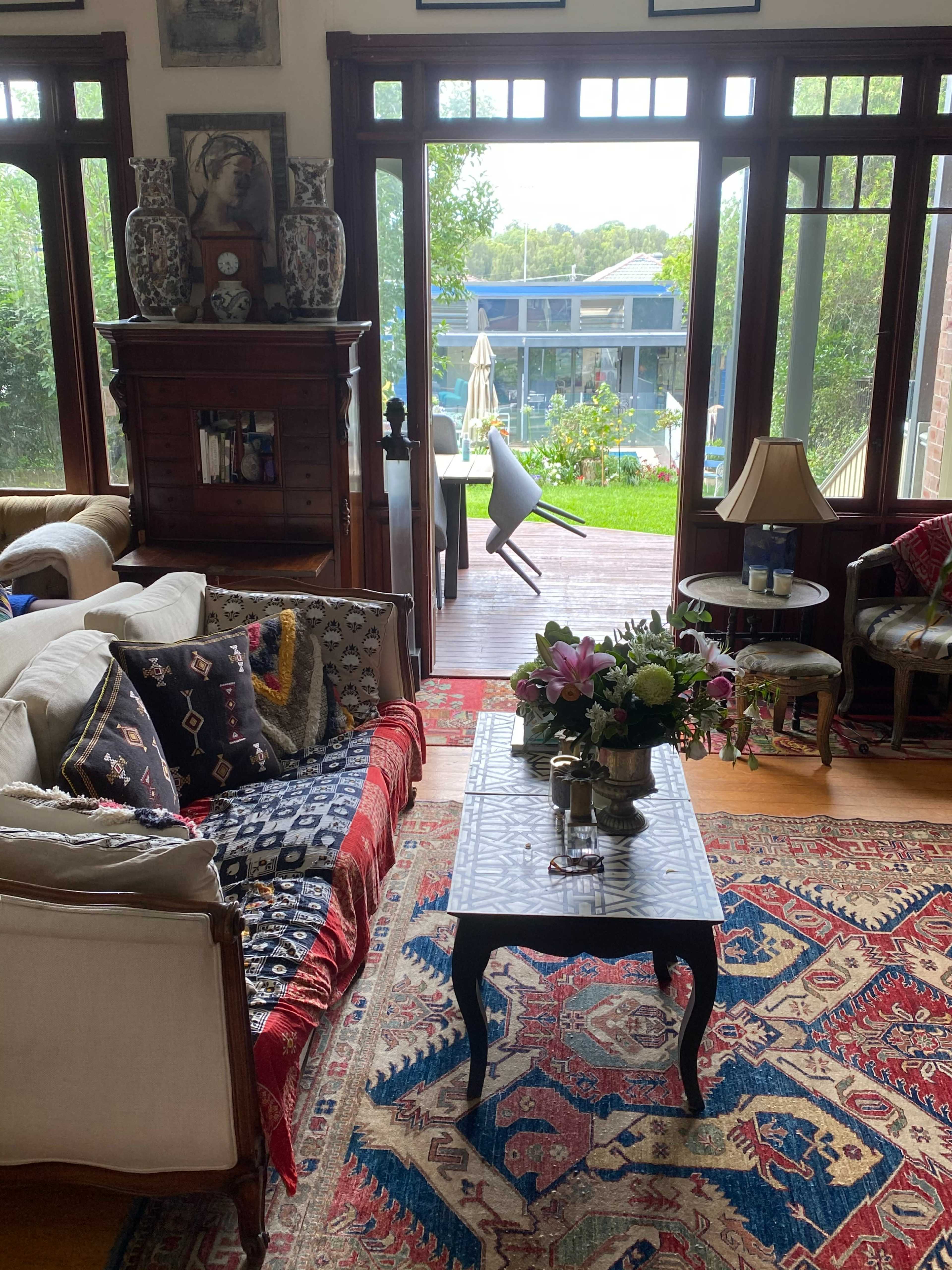 A living room filled with various seating arrangements and decor leads to a patio area with a pool visible through the open door.