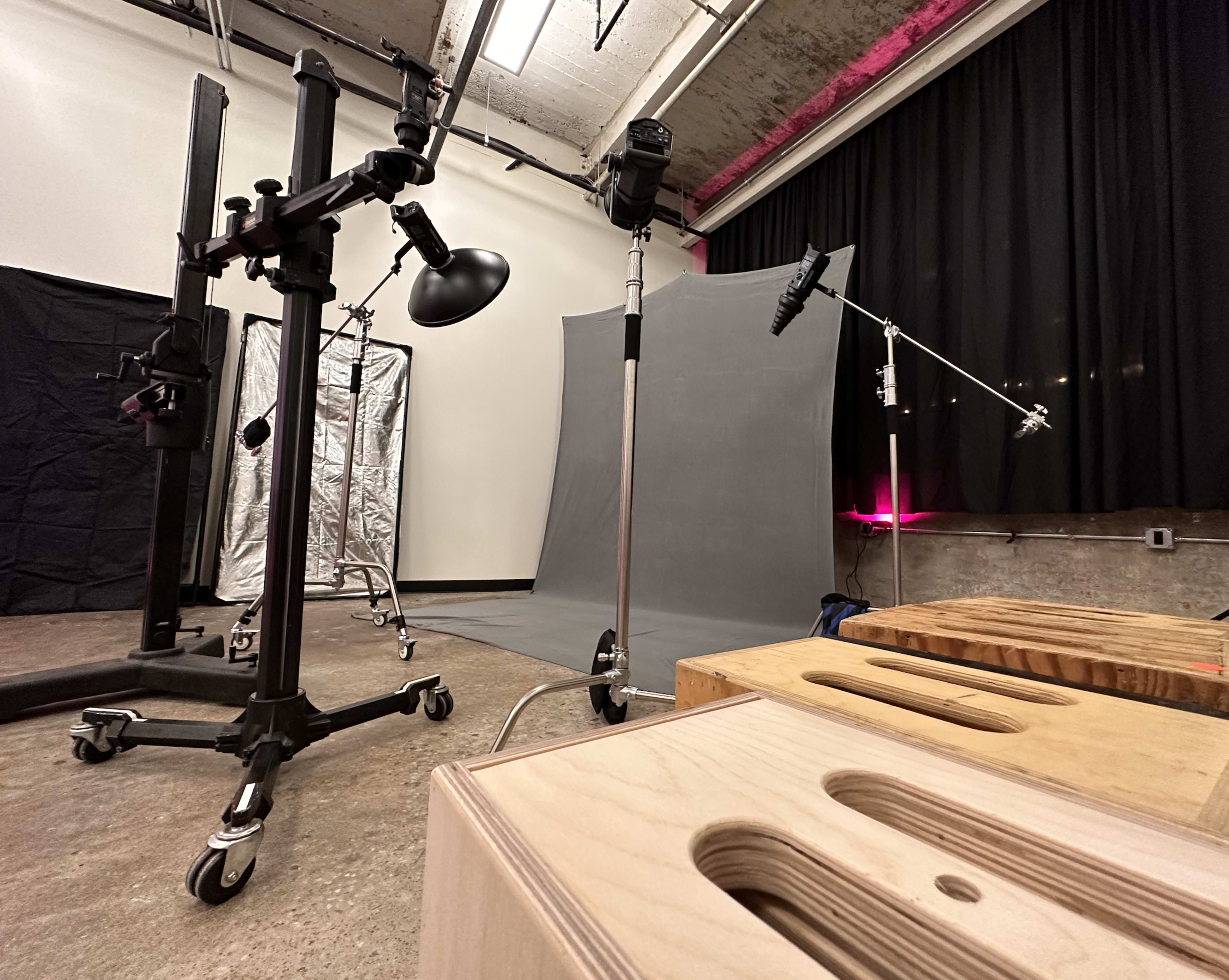 A photography studio setup with various equipment, including light stands, backdrops, and wooden blocks for support.