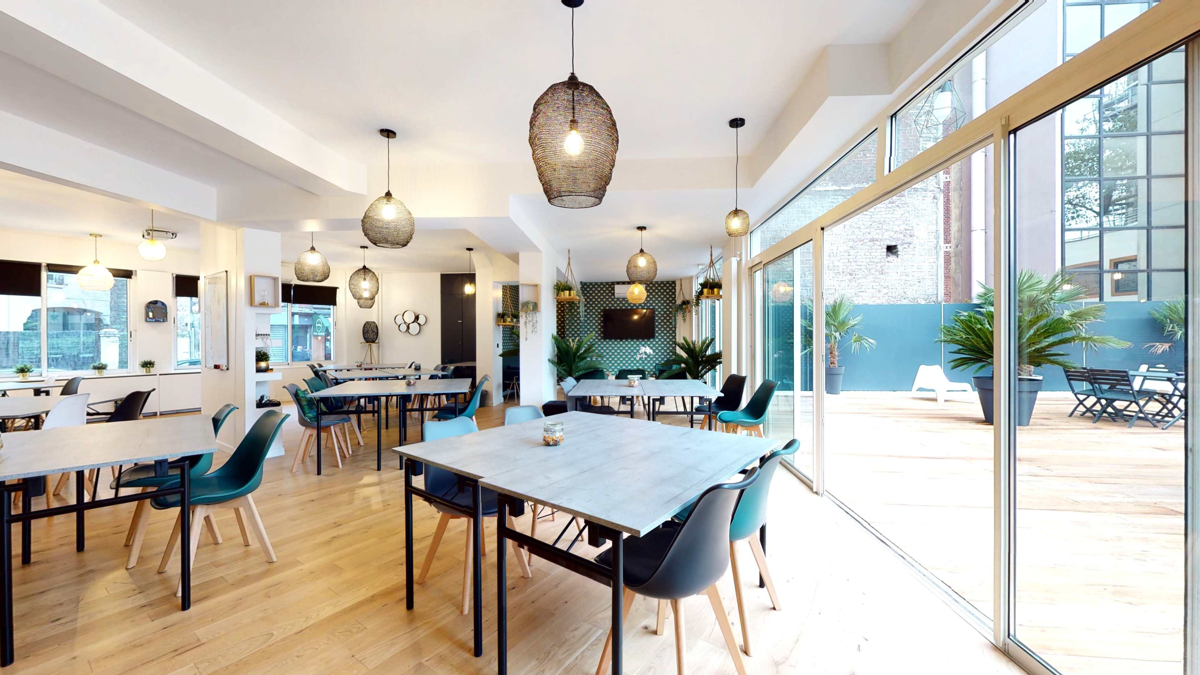 A spacious dining area features wooden tables and chairs, large windows, and modern lighting fixtures.