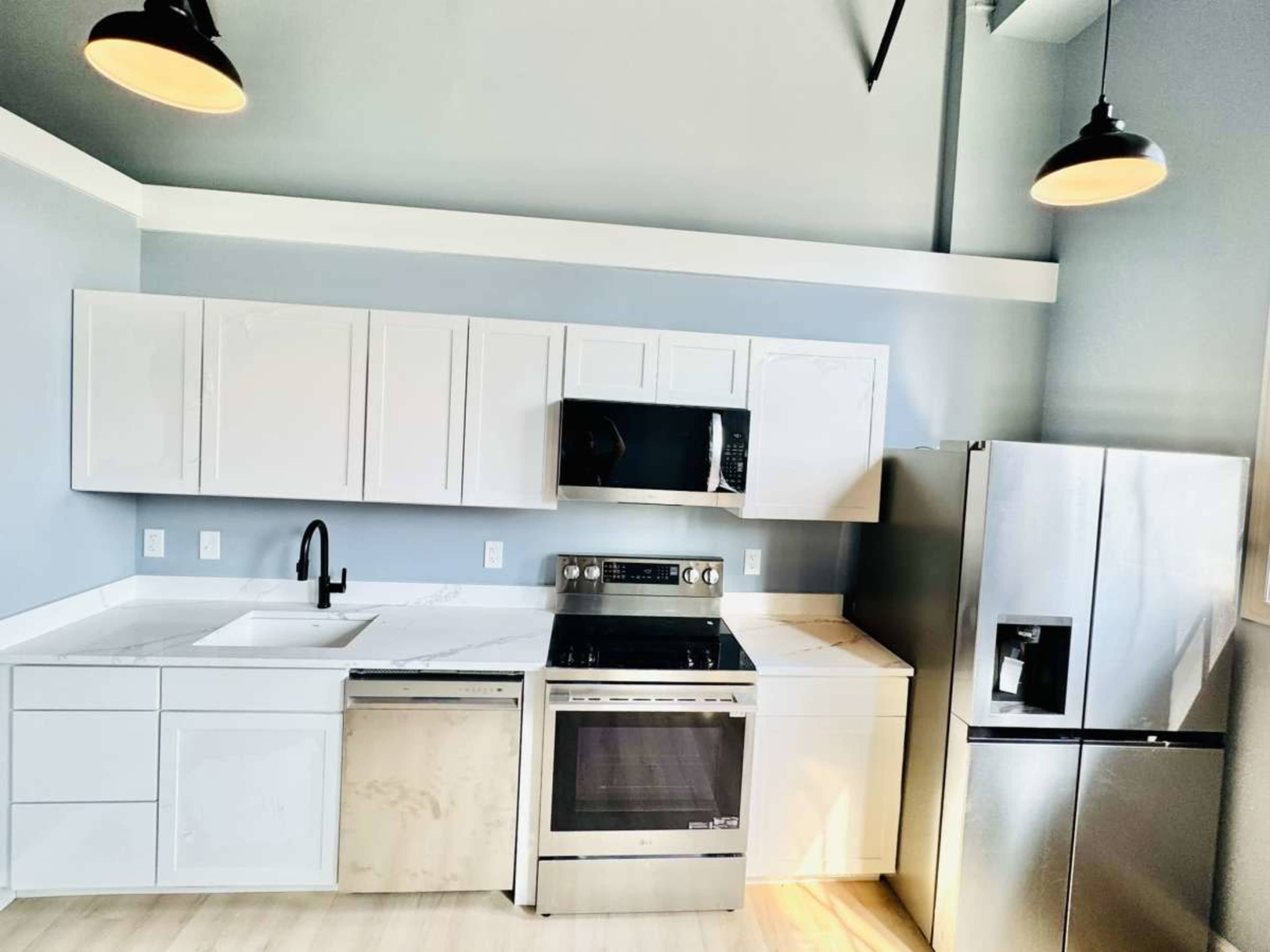 The image shows a modern kitchen featuring white cabinetry, stainless steel appliances, and a light-colored countertop.