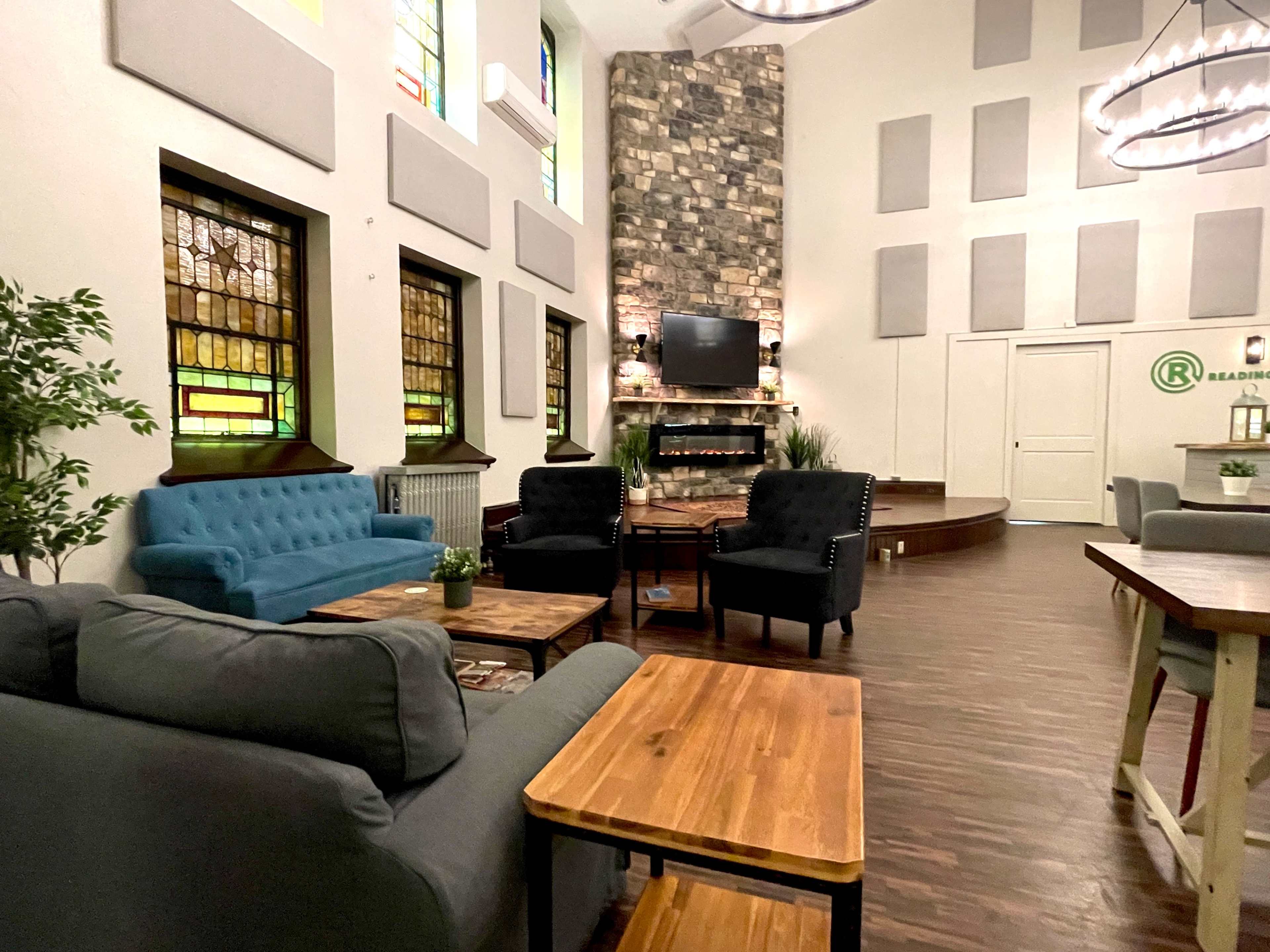 A cozy interior space with stained glass windows, comfortable seating, and a stone fireplace.