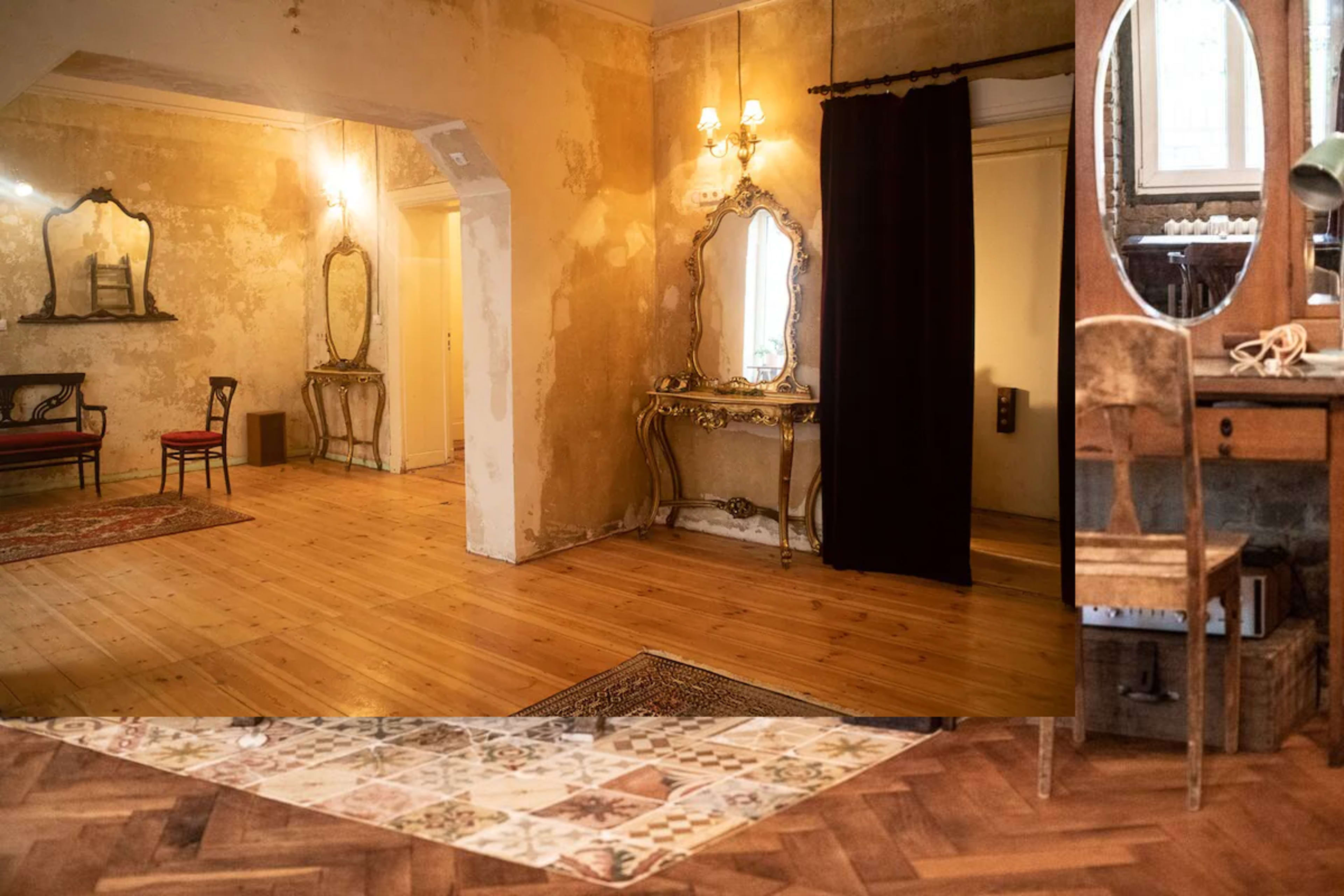 The room features a mix of vintage mirrors and furniture, with a wooden floor and a patterned area rug, set in a space with distressed walls and soft lighting.