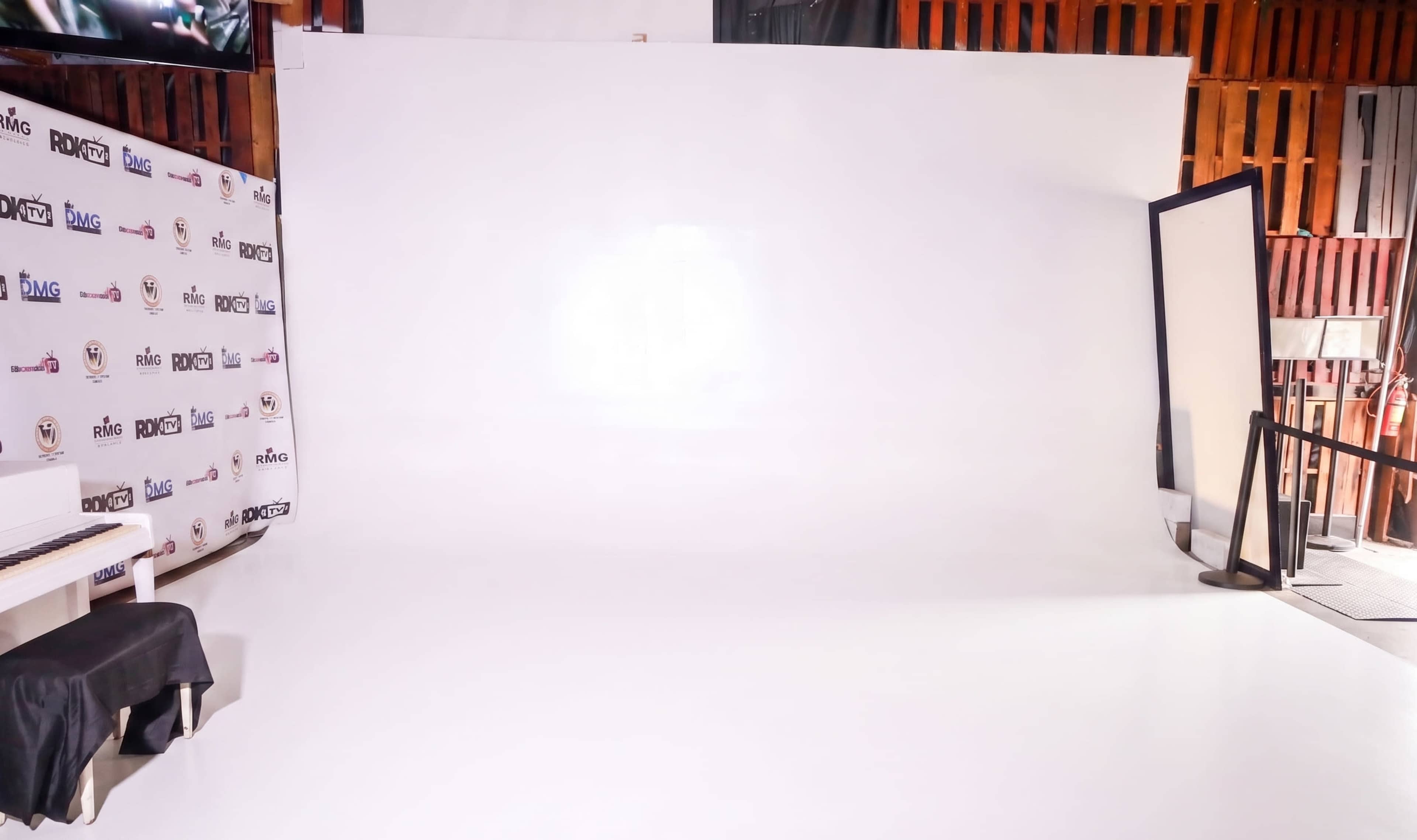 The image shows a spacious photo studio with a white backdrop and a large mirror on the right side.