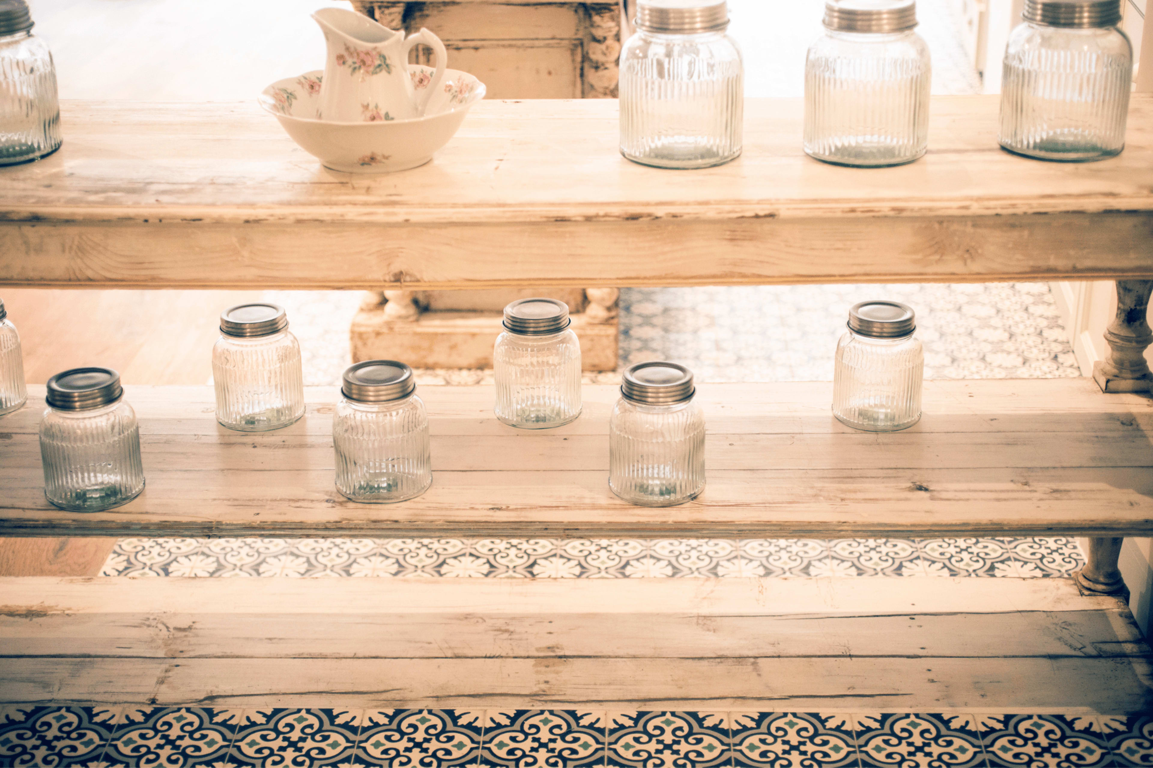 A wooden shelf displays several glass jars and a decorative bowl.