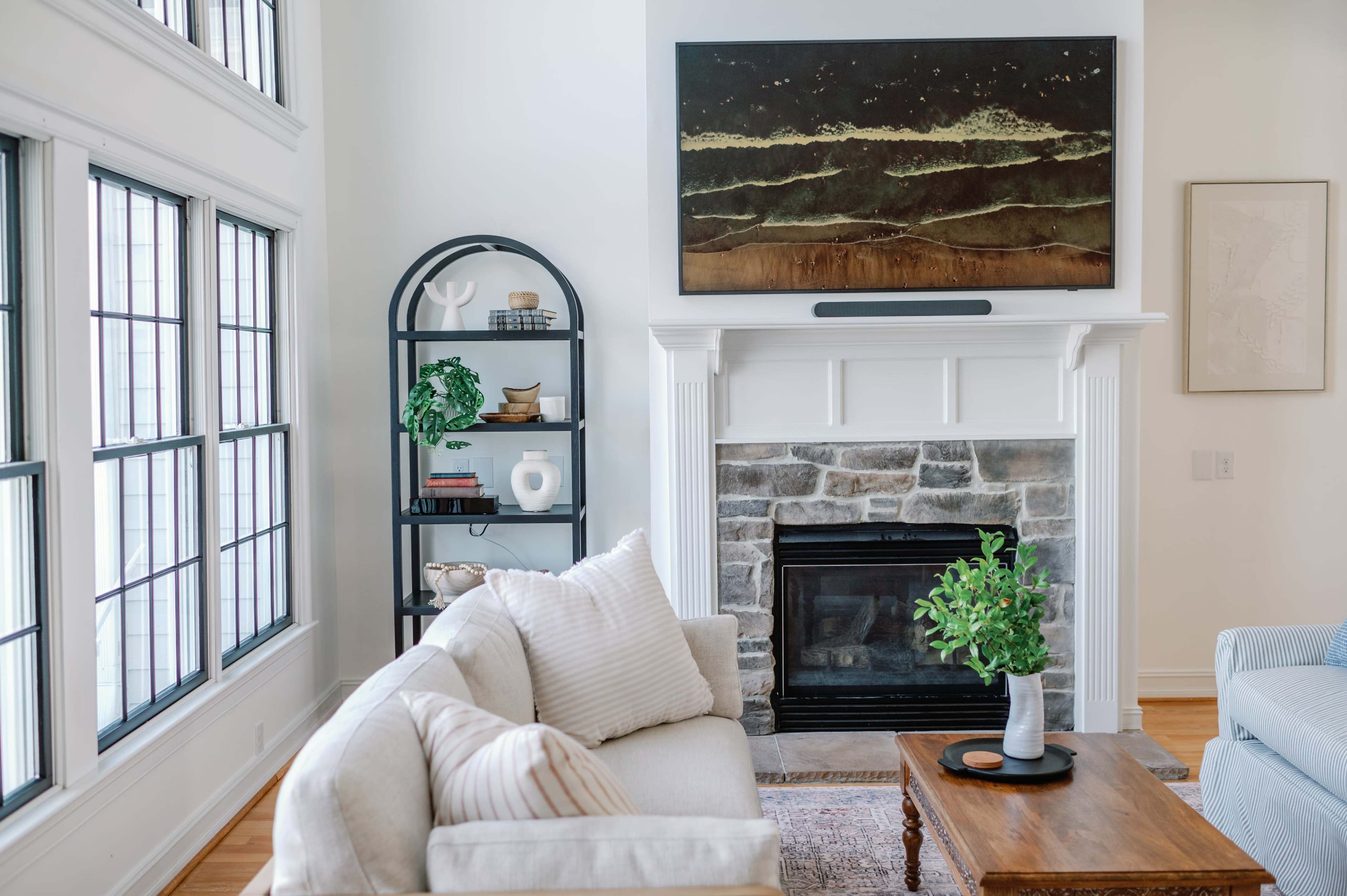 A living room with a fireplace, a mounted art piece above it, a wooden coffee table, and a comfortable sofa.