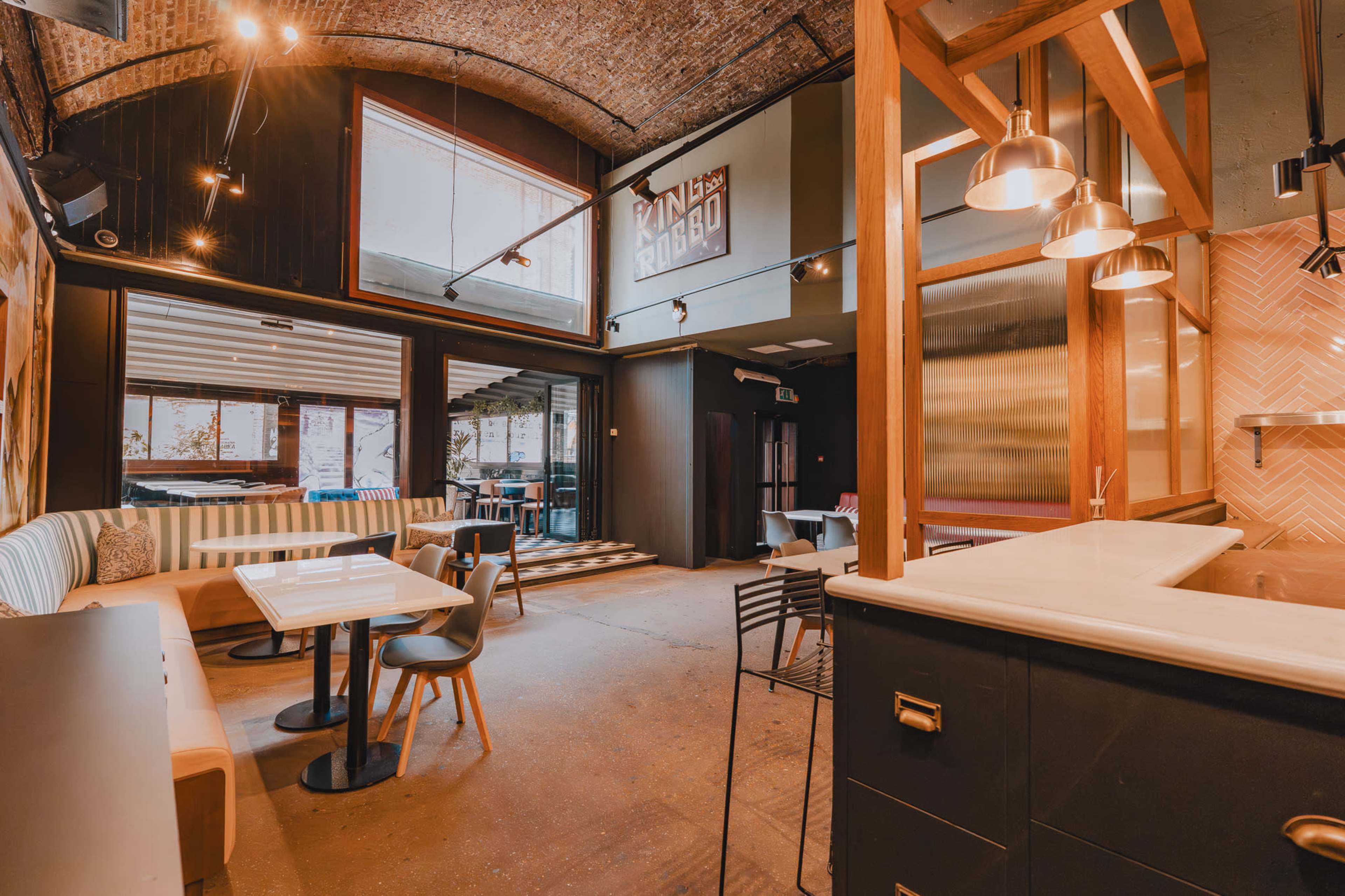 The interior of a modern cafe features a mix of seating arrangements, large windows, and stylish lighting.