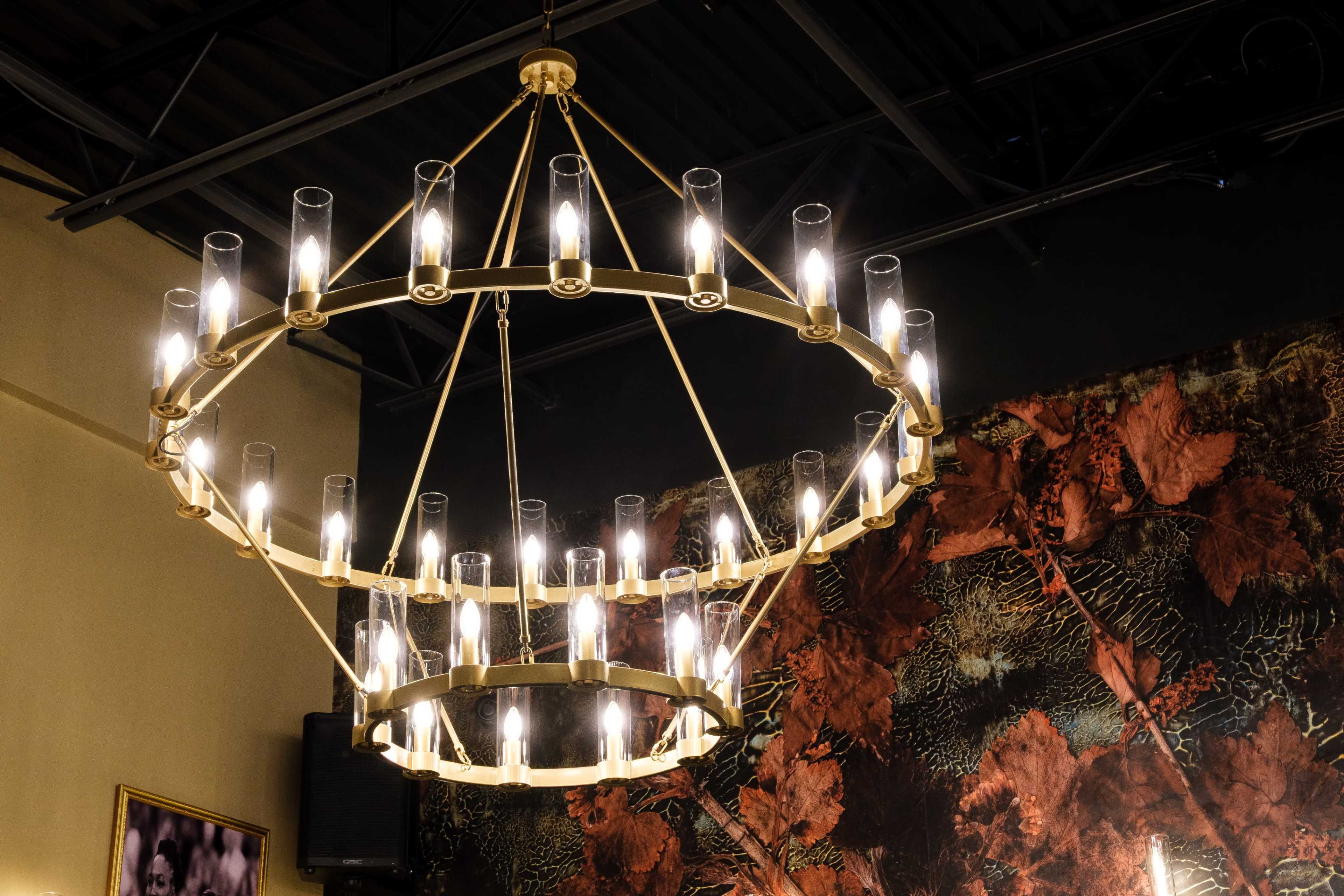 A large, circular chandelier with multiple clear glass tubes and bulbs hangs from the ceiling, illuminating the space below.