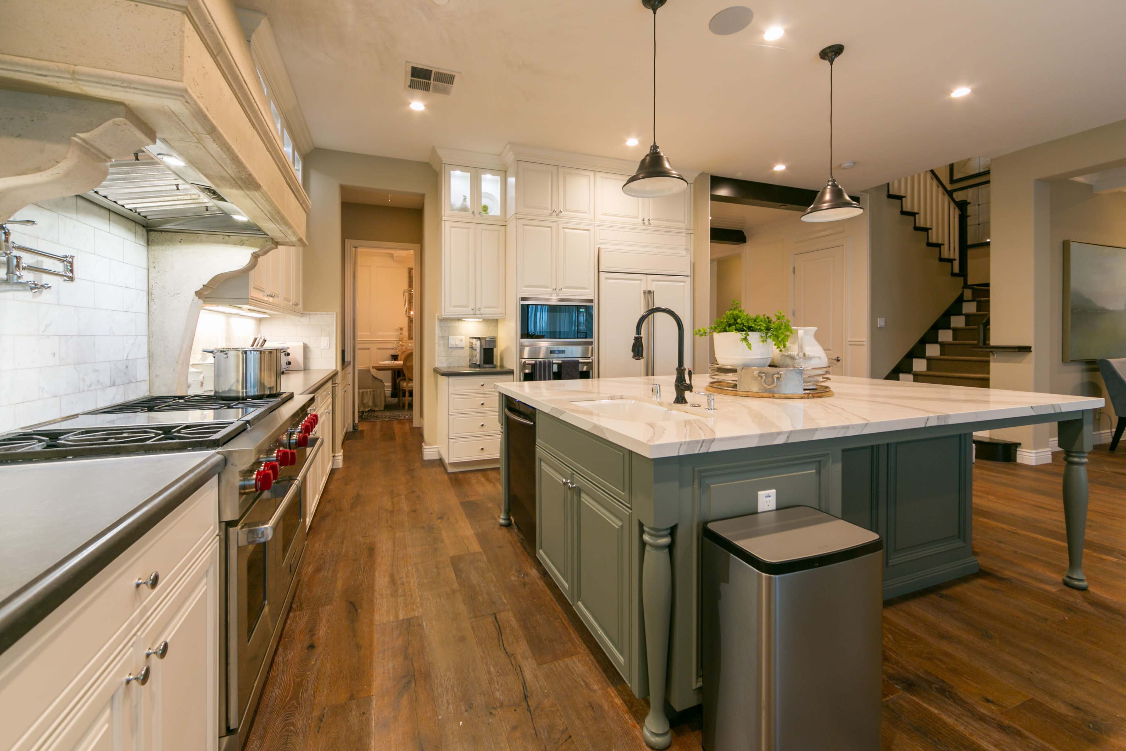 A modern kitchen with a large island, stainless steel appliances, and light wood flooring.