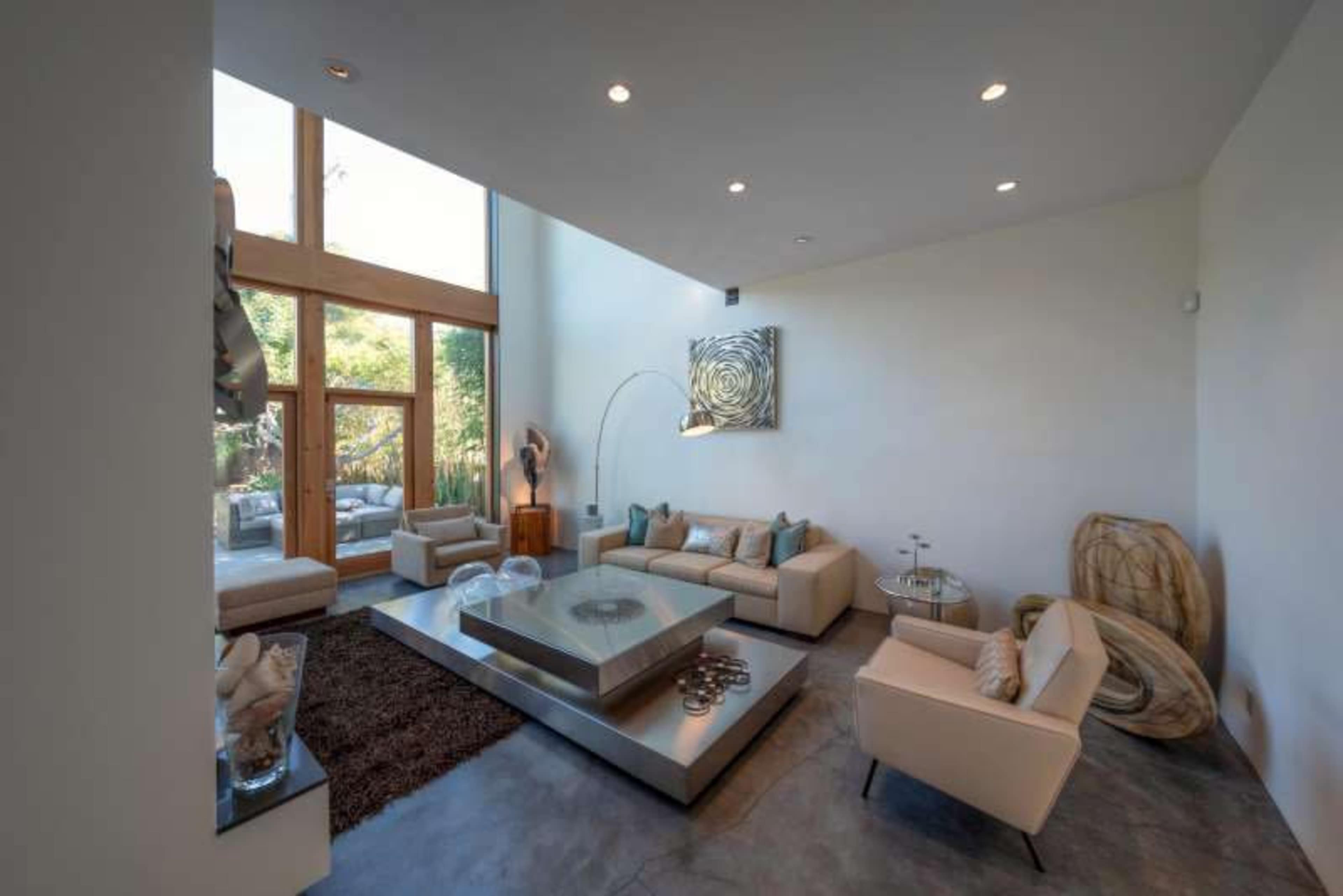 A modern living room features a large window, minimalistic furniture, and a central coffee table.