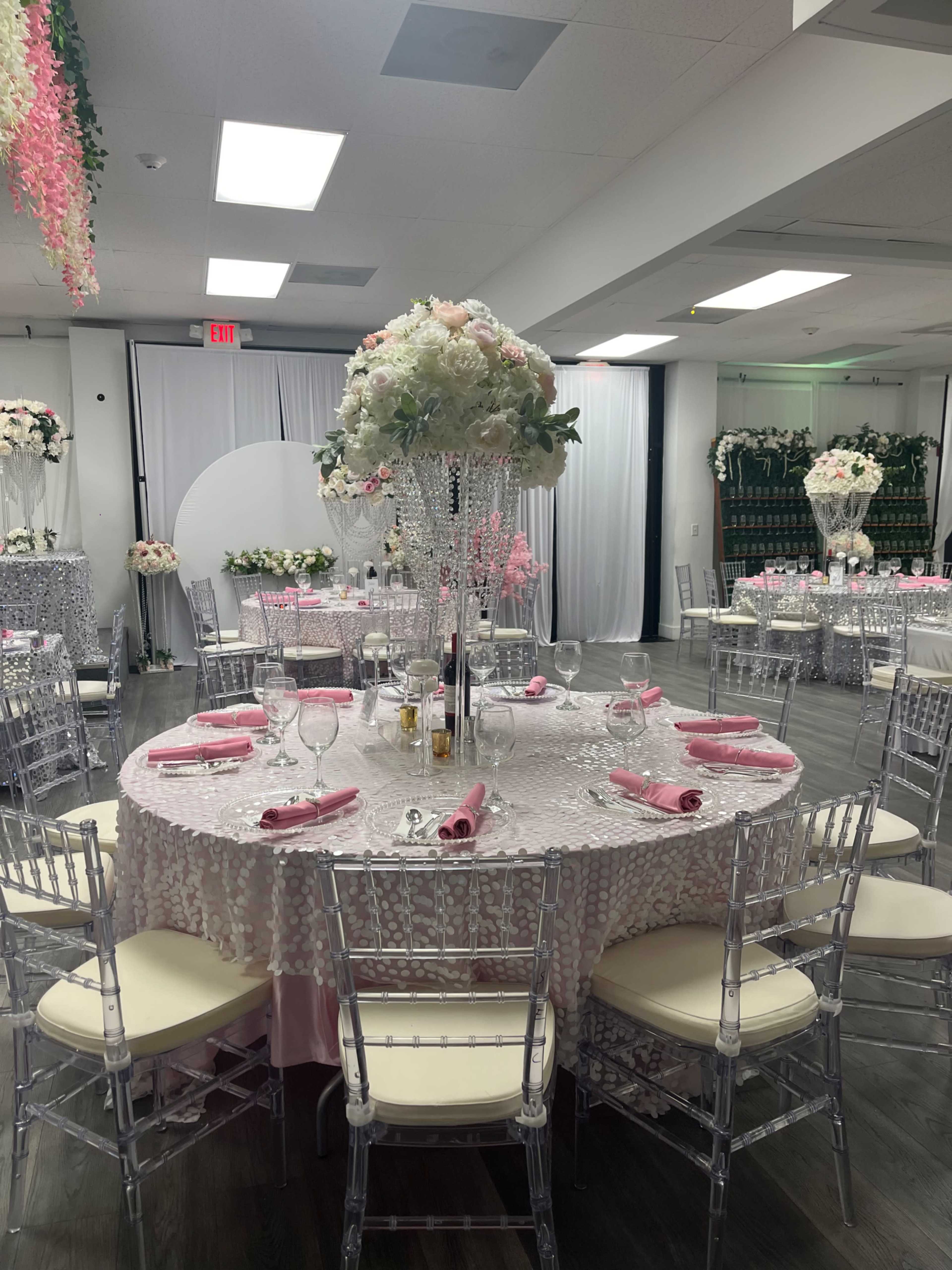 A beautifully arranged banquet setting with round tables dressed in sequined tablecloths, elegant chairs, and floral centerpieces, all set for an event.
