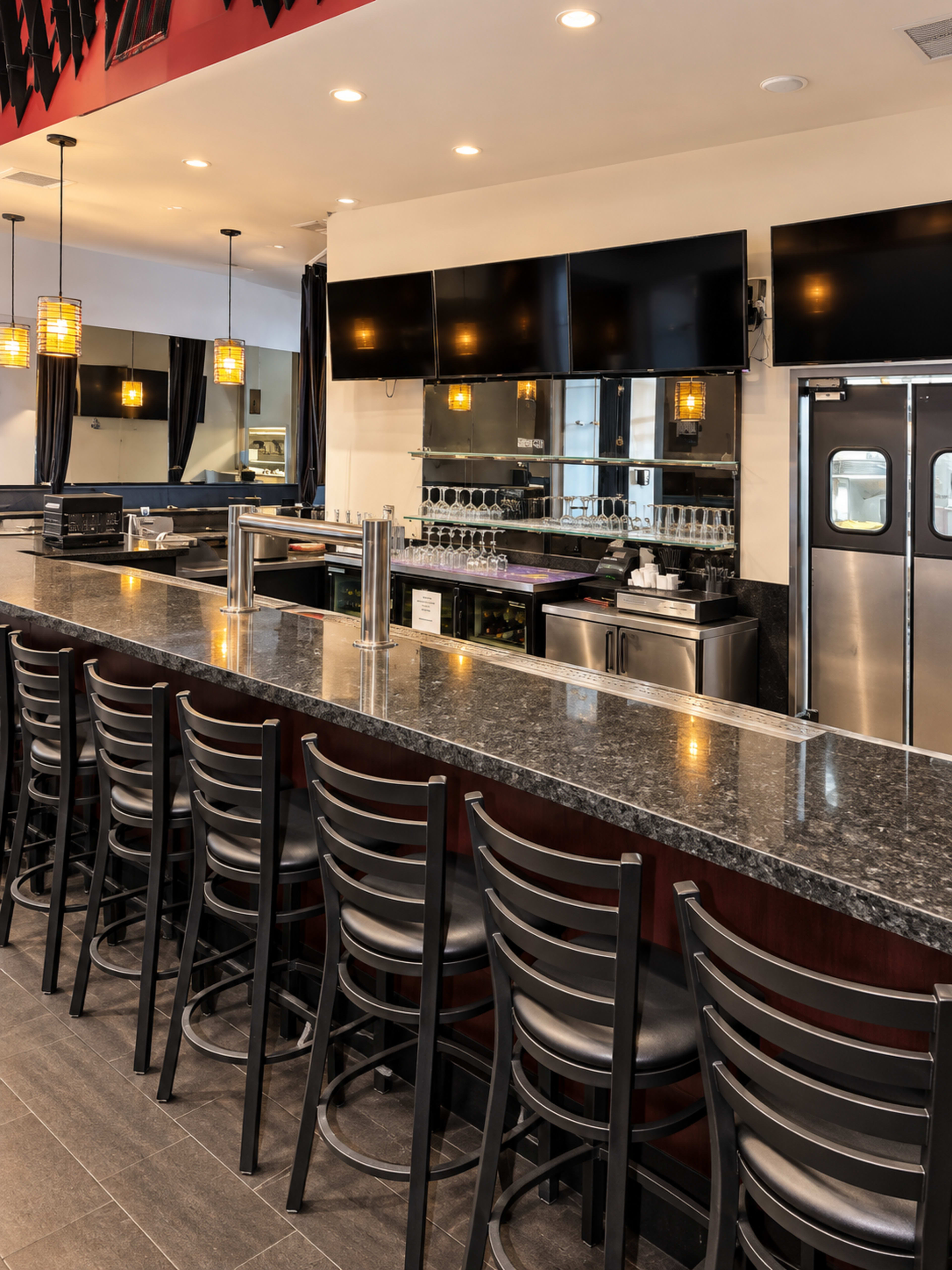 The image shows a modern bar area with a long granite countertop, high back chairs, and multiple flat-screen TVs mounted on the wall.