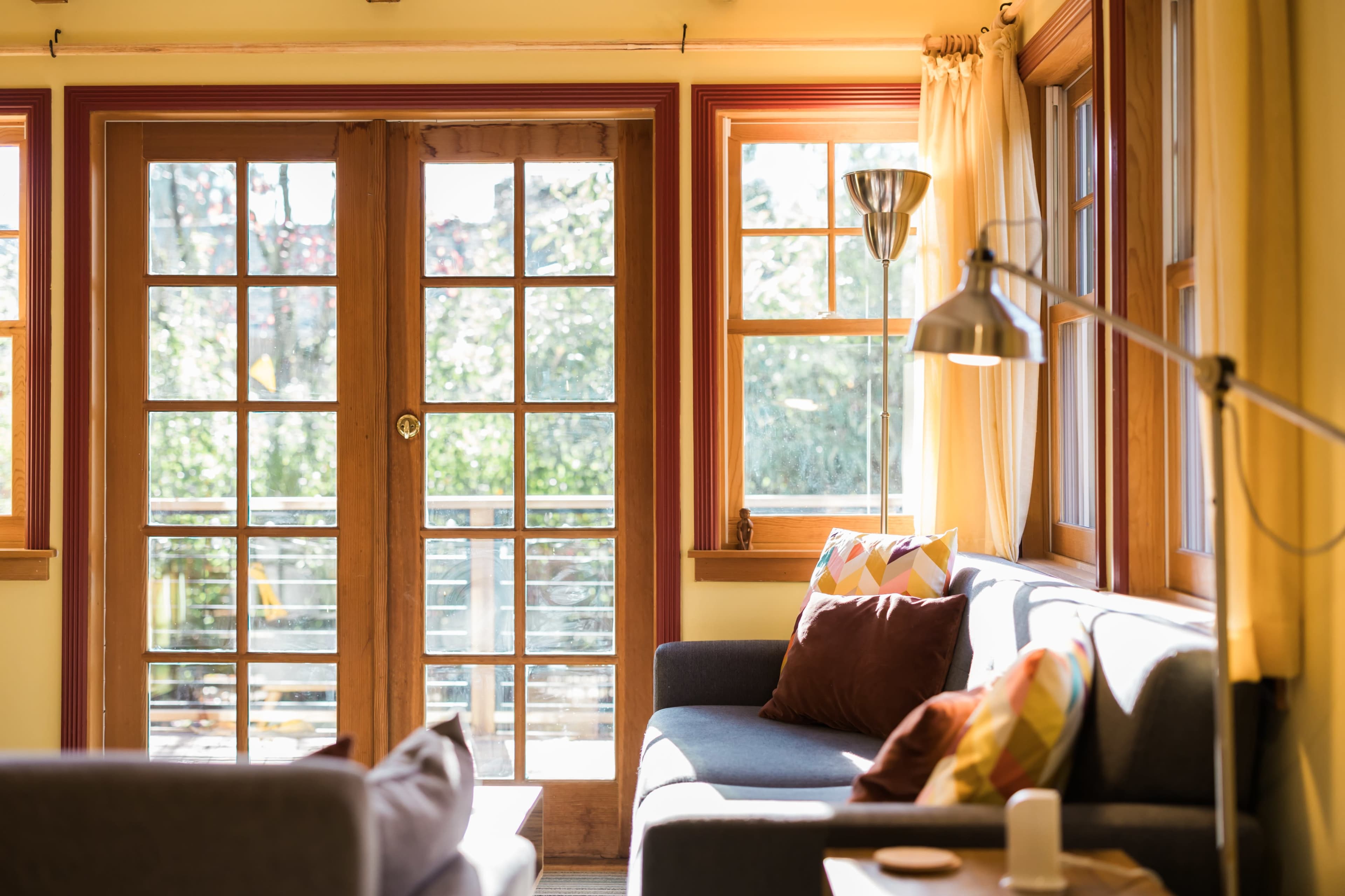 The image shows a well-lit living room with large windows, a sofa, and a coffee table.