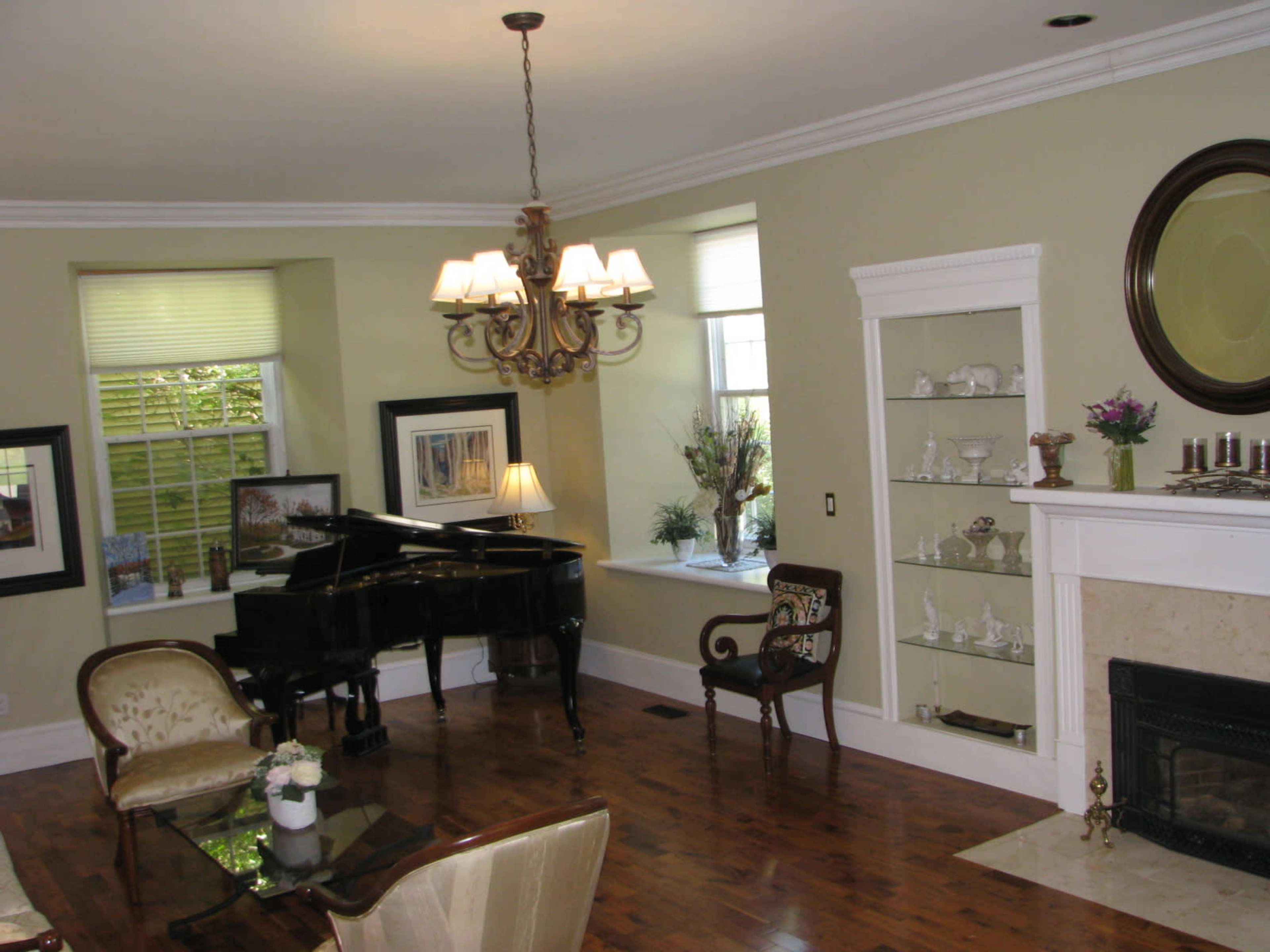 A spacious living room featuring a grand piano, a dining area, and a decorative fireplace with a built-in display case.