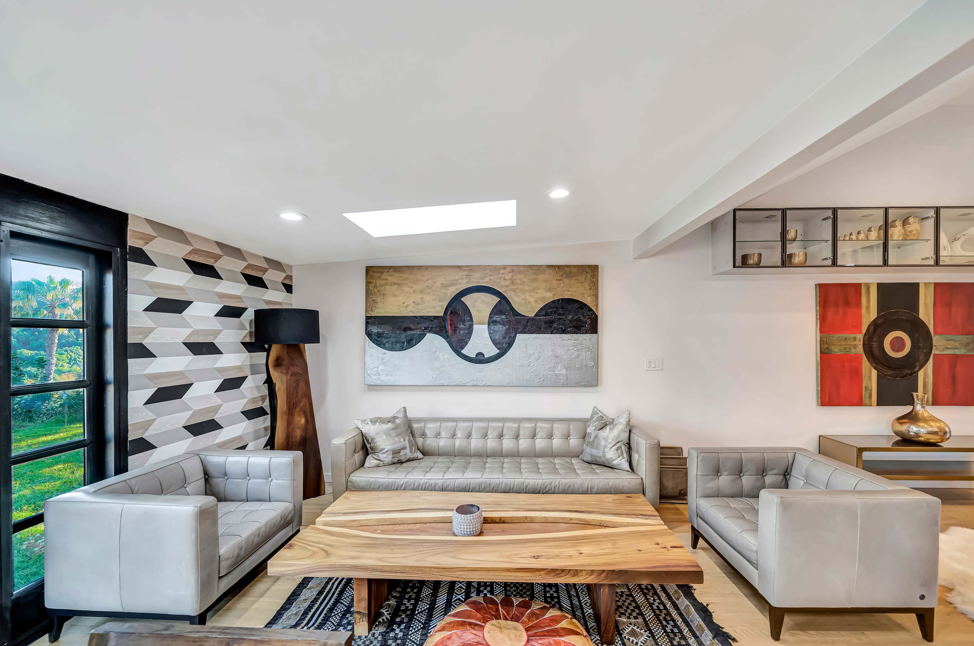 A modern living room with a large wooden coffee table, two gray sofas, and decorative artwork on the walls.