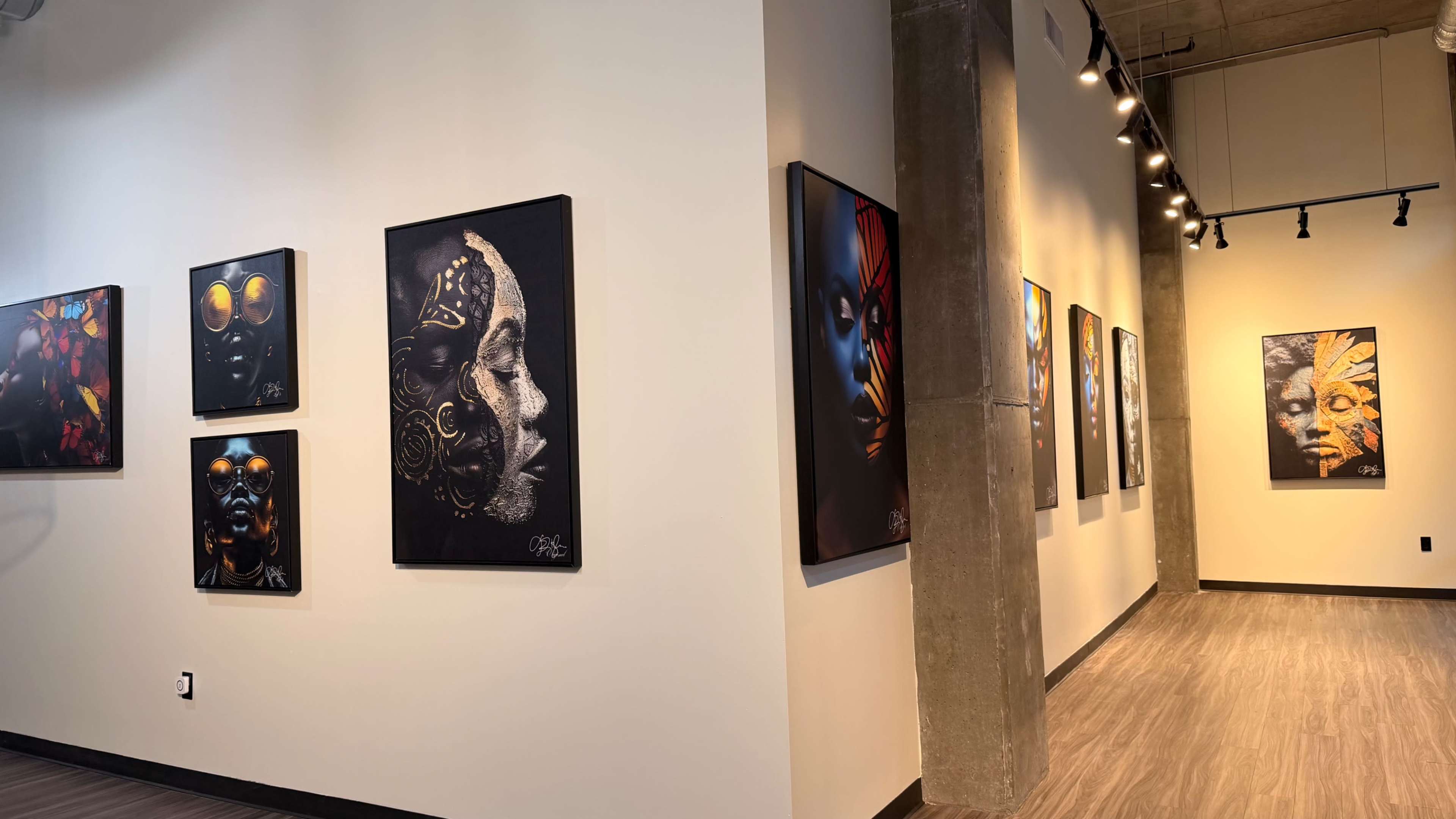 The image shows an art gallery with a series of colorful paintings depicting faces, arranged on the walls of a well-lit corridor.