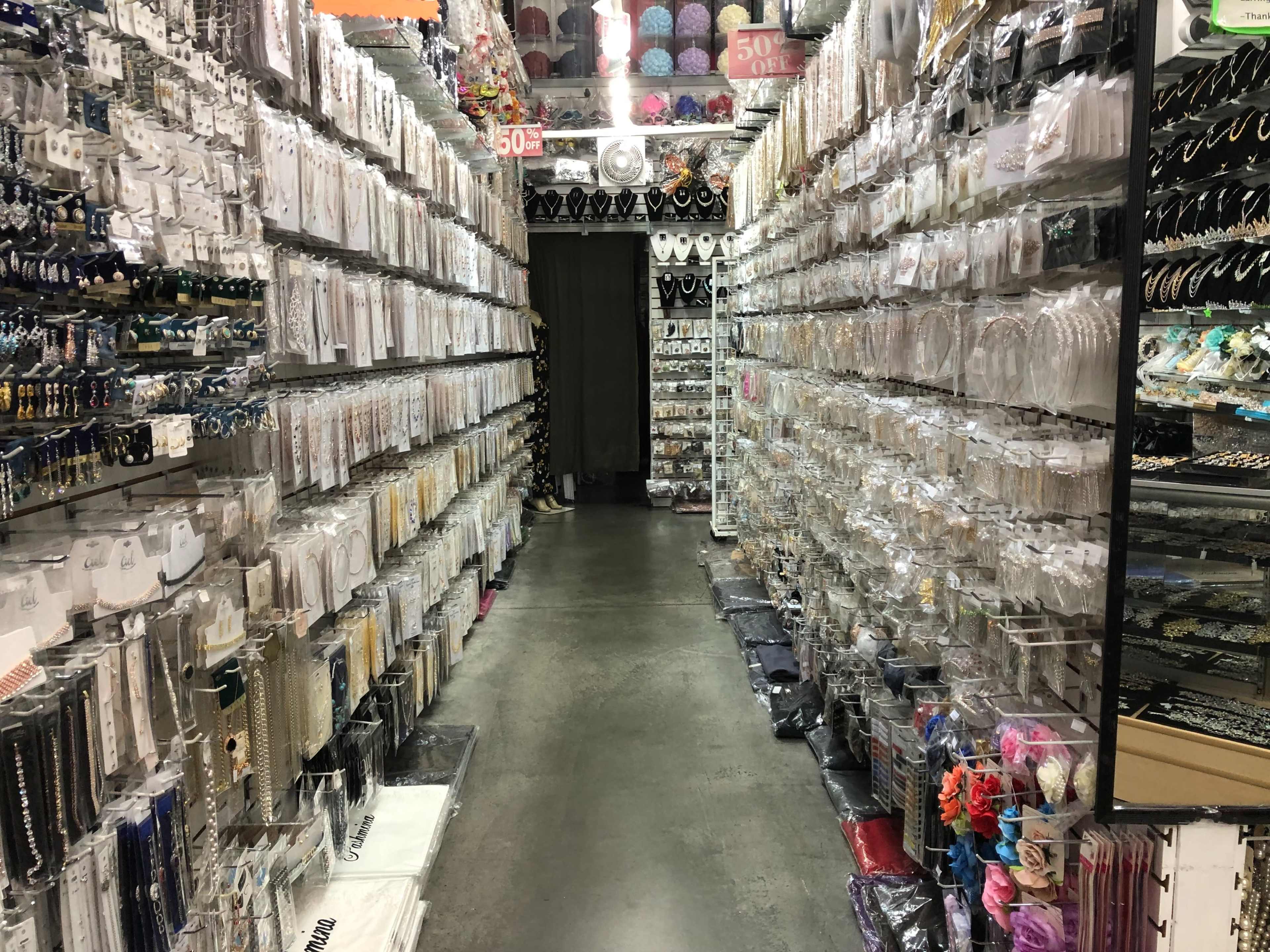 The image shows a narrow aisle in a retail store lined with shelves filled with various accessories and jewelry items.