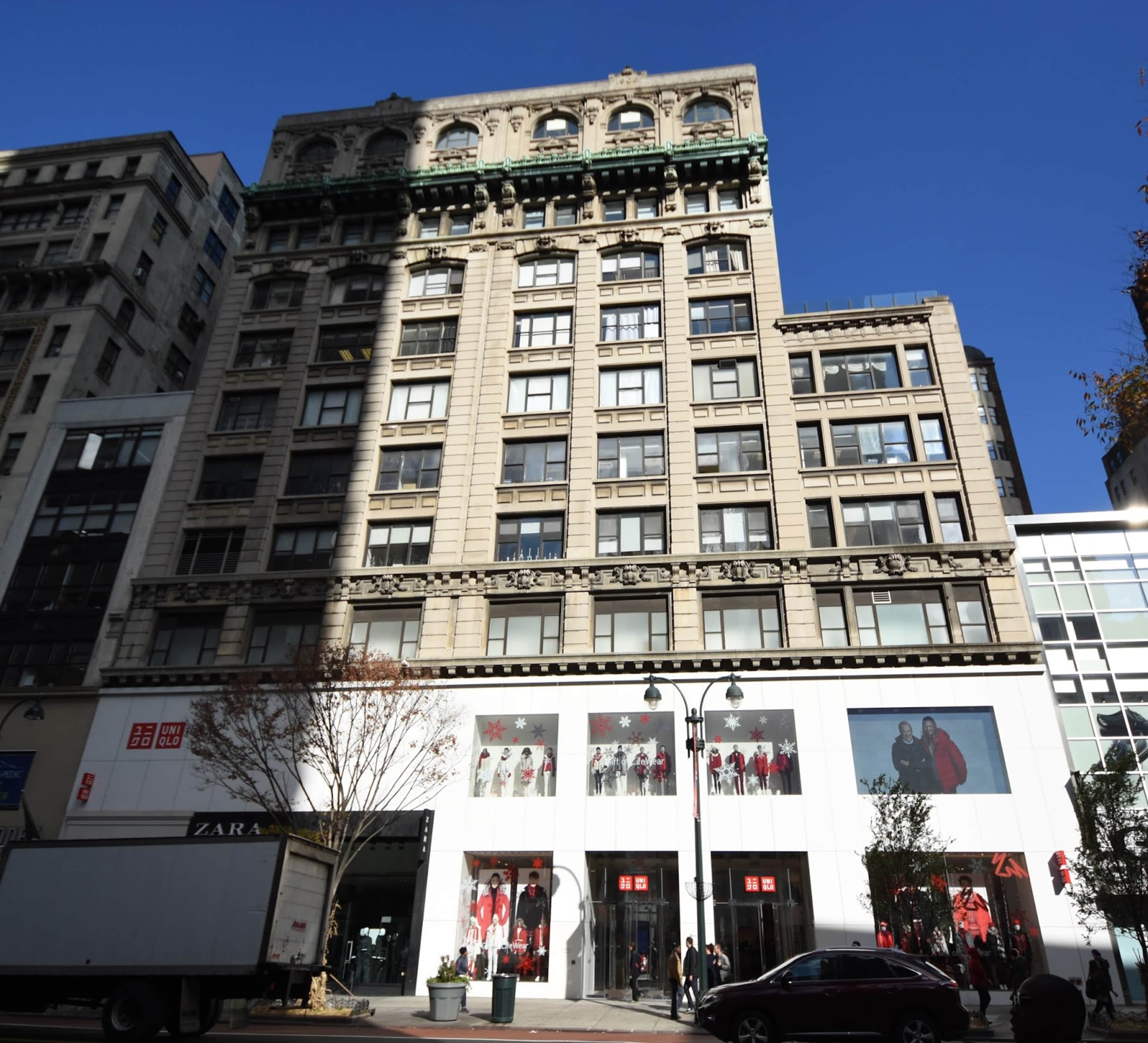 A multi-story building with a mixture of contemporary and historic architectural features, along with retail storefronts at the ground level.