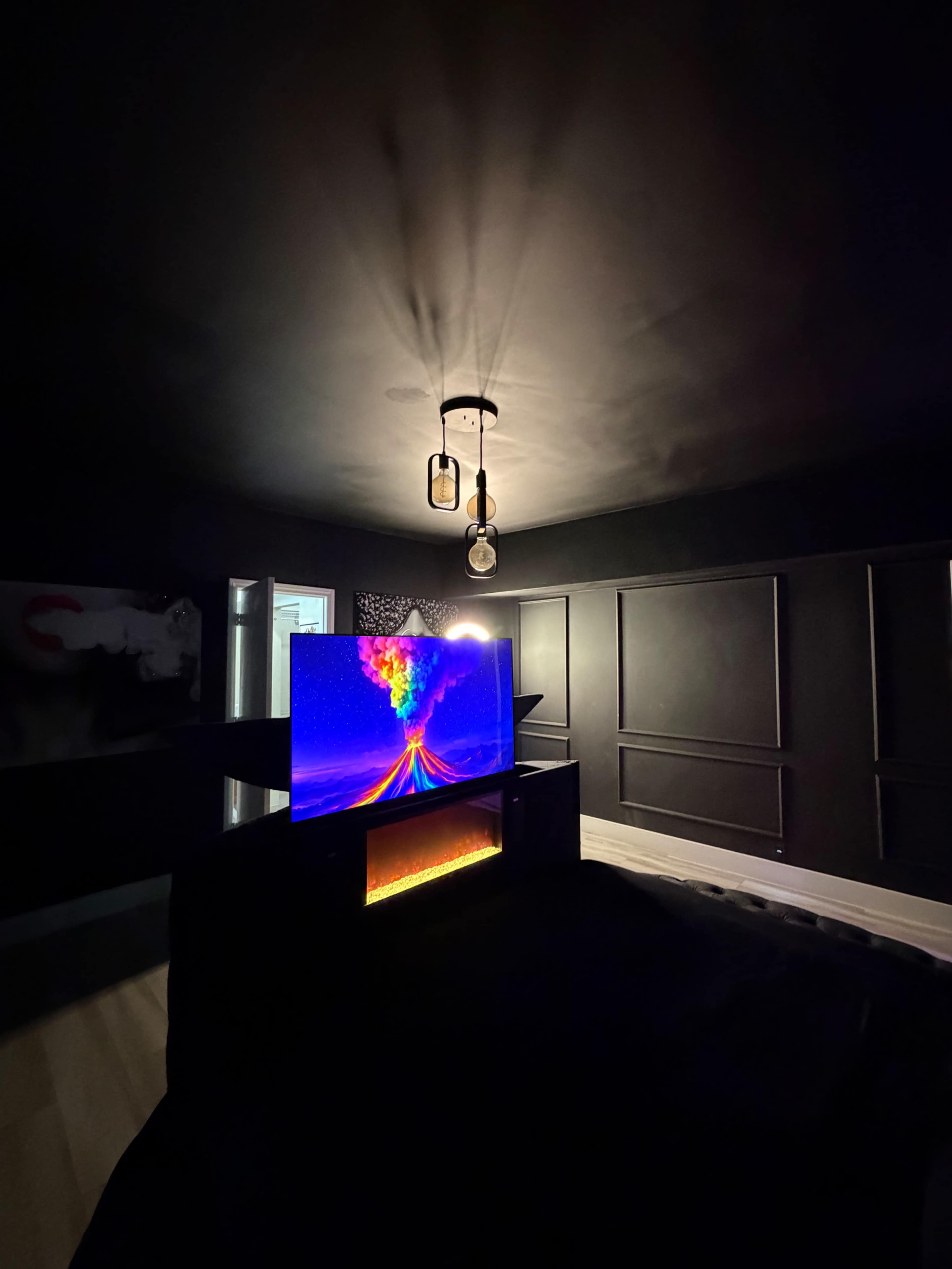 A brightly colored television displaying a vibrant graphic sits on a dark-finished entertainment unit in a dimly lit room.