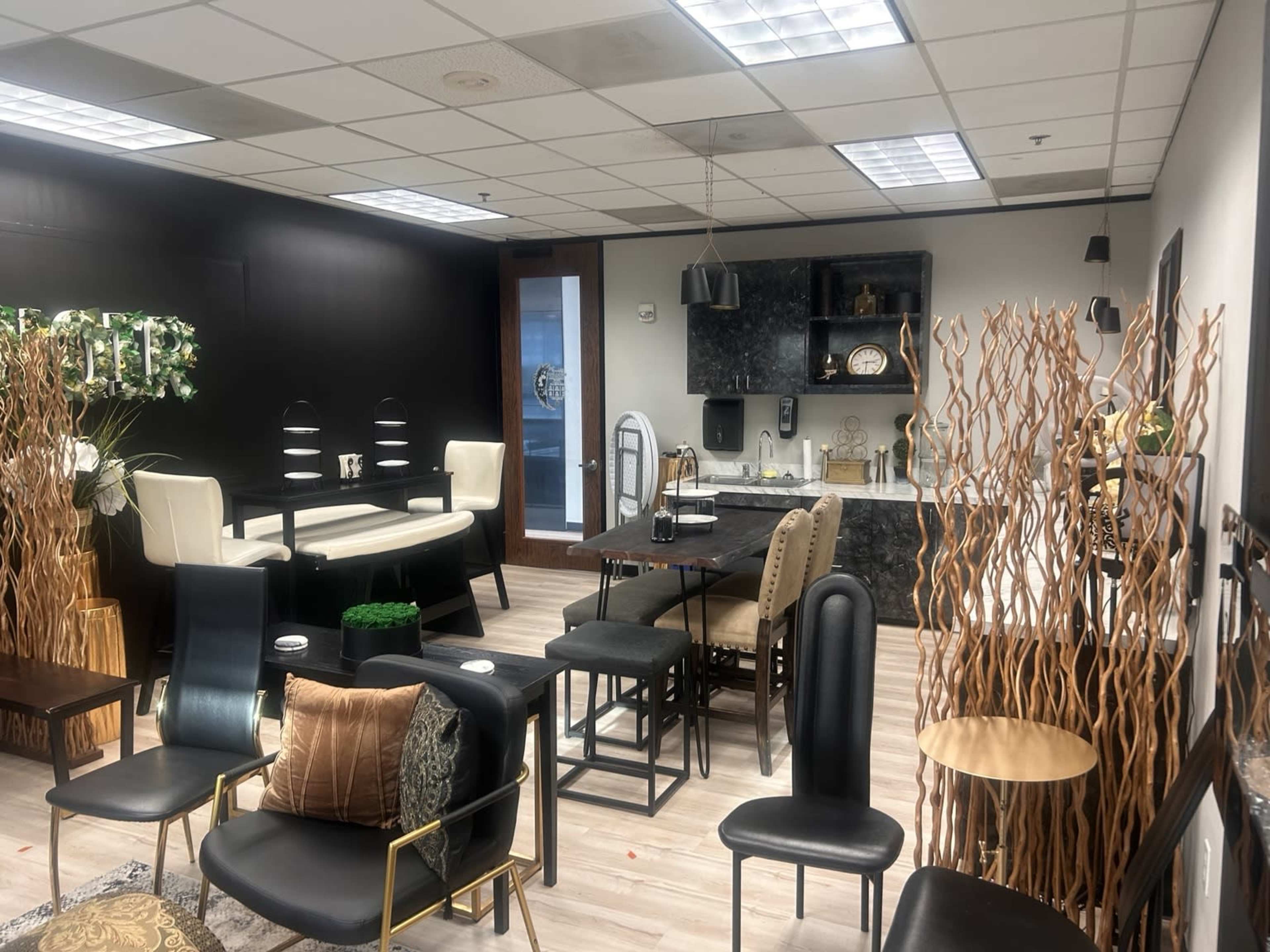 The image shows a modern office or lounge area with various seating arrangements, including tables and chairs, along with decorative elements like plants and wooden accents.